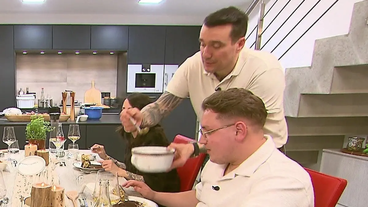 Freddy serviert etwas aus einem Topf direkt auf den Teller eines Gastes.