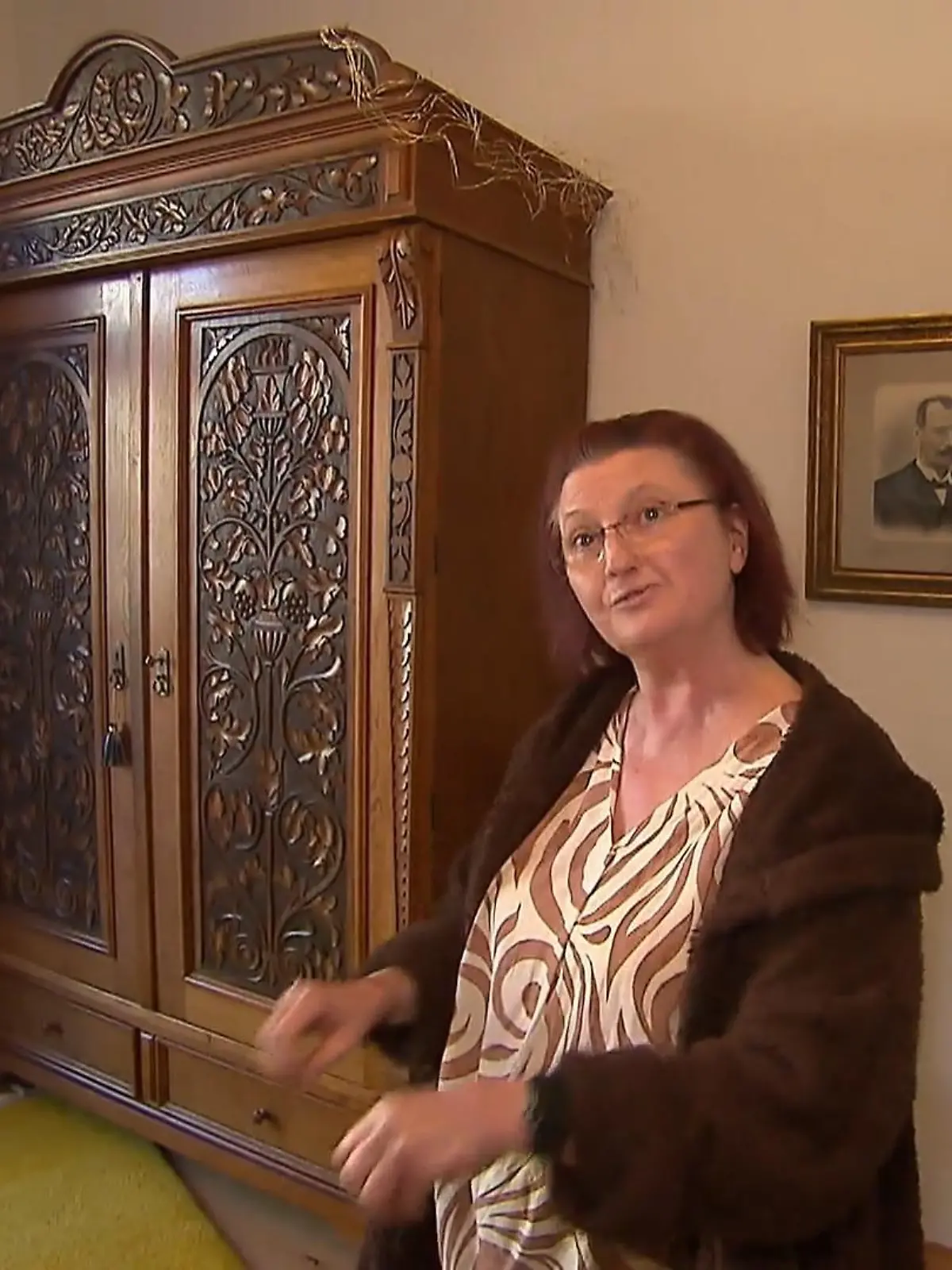 Katja steht vor einem schmuckvoll verzierten Holzschrank.