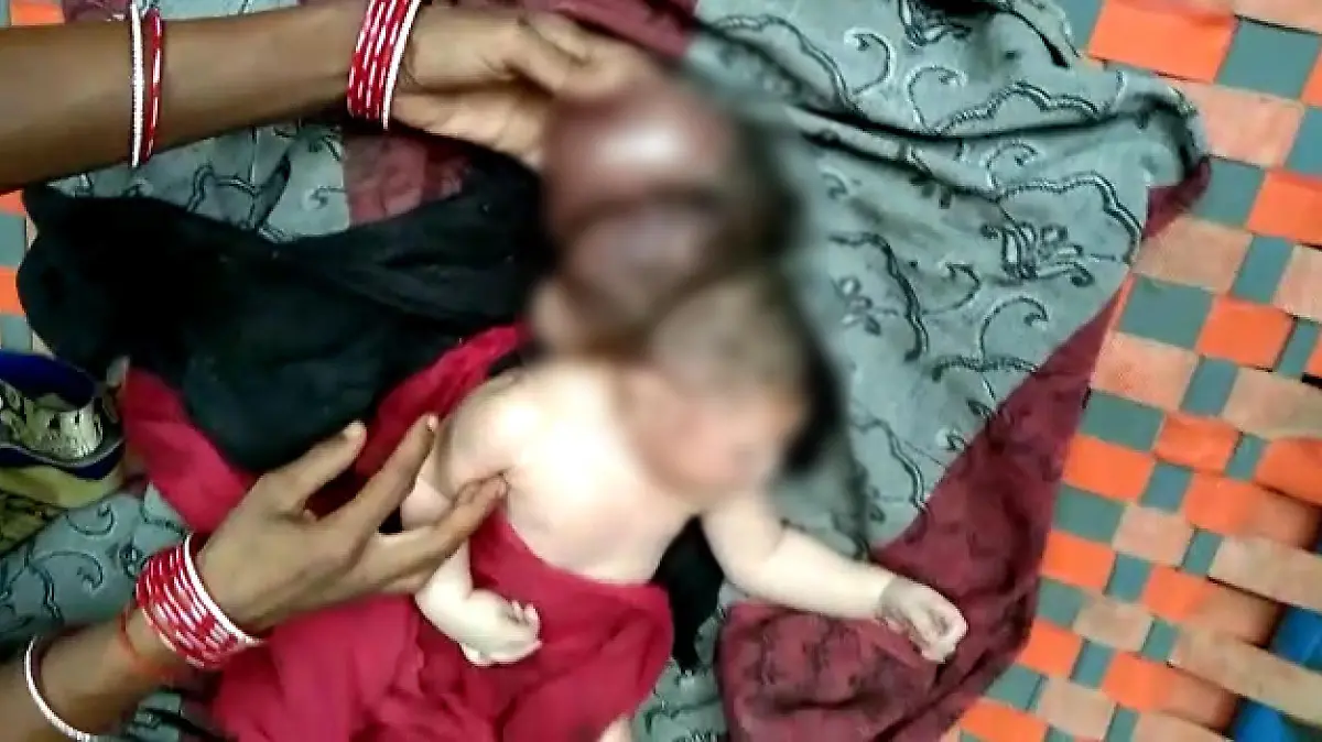Ein Baby liegt auf einem Handtuch. Hinter dem Kopf des Babys erkennt man zwei weitere Köpfe.