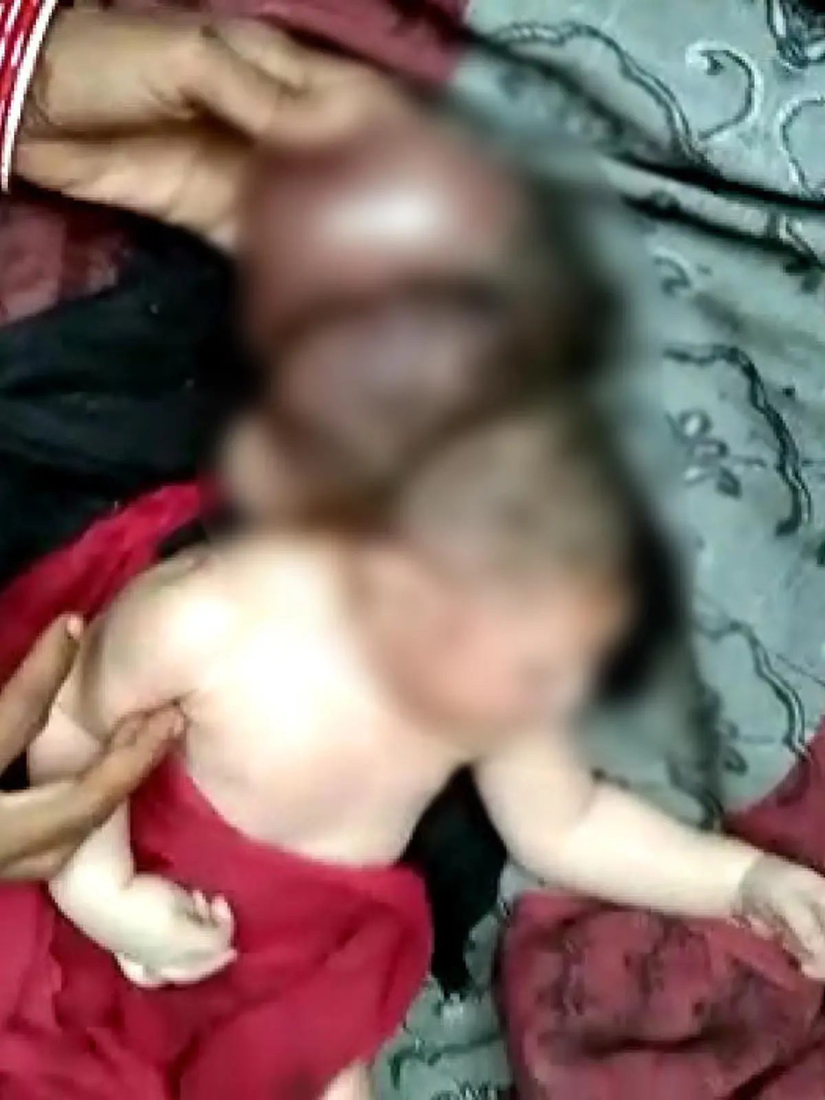 Ein Baby liegt auf einem Handtuch. Hinter dem Kopf des Babys erkennt man zwei weitere Köpfe.