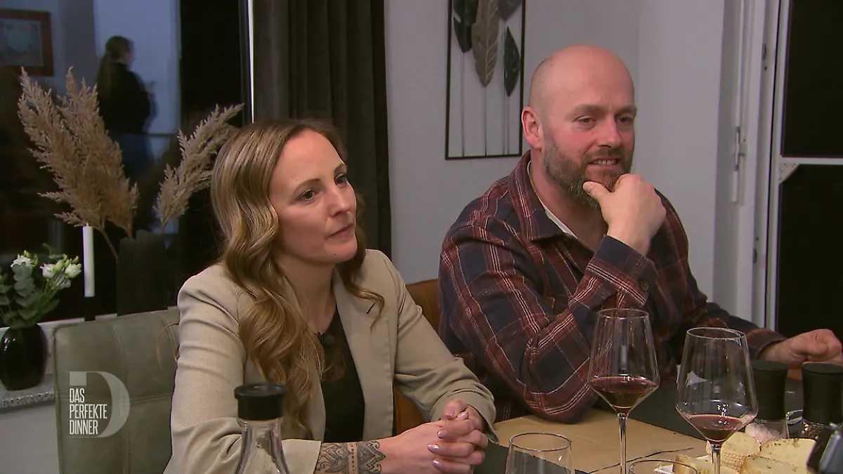 Zwei Gäste sitzen bei Rotwein am Tisch.