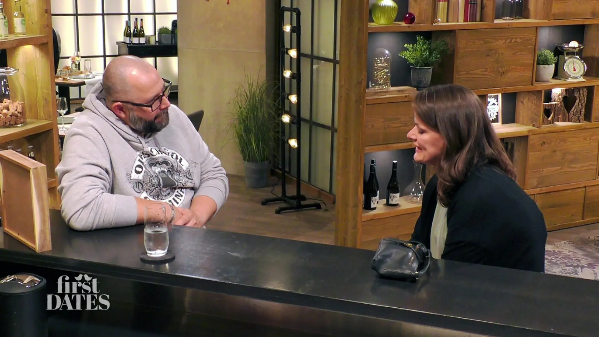 Lars und Anne sitzen am Tresen beisammen und unterhalten sich.