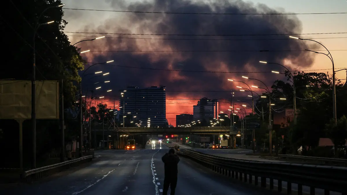 A man takes a picture of a street as smoke rises in the background after an overnight Russian missile and drone strike, amid Russia's attack on Ukraine, in Kyiv, Ukraine June 2, 2026. REUTERS/Alina Smutko TPX IMAGES OF THE DAY