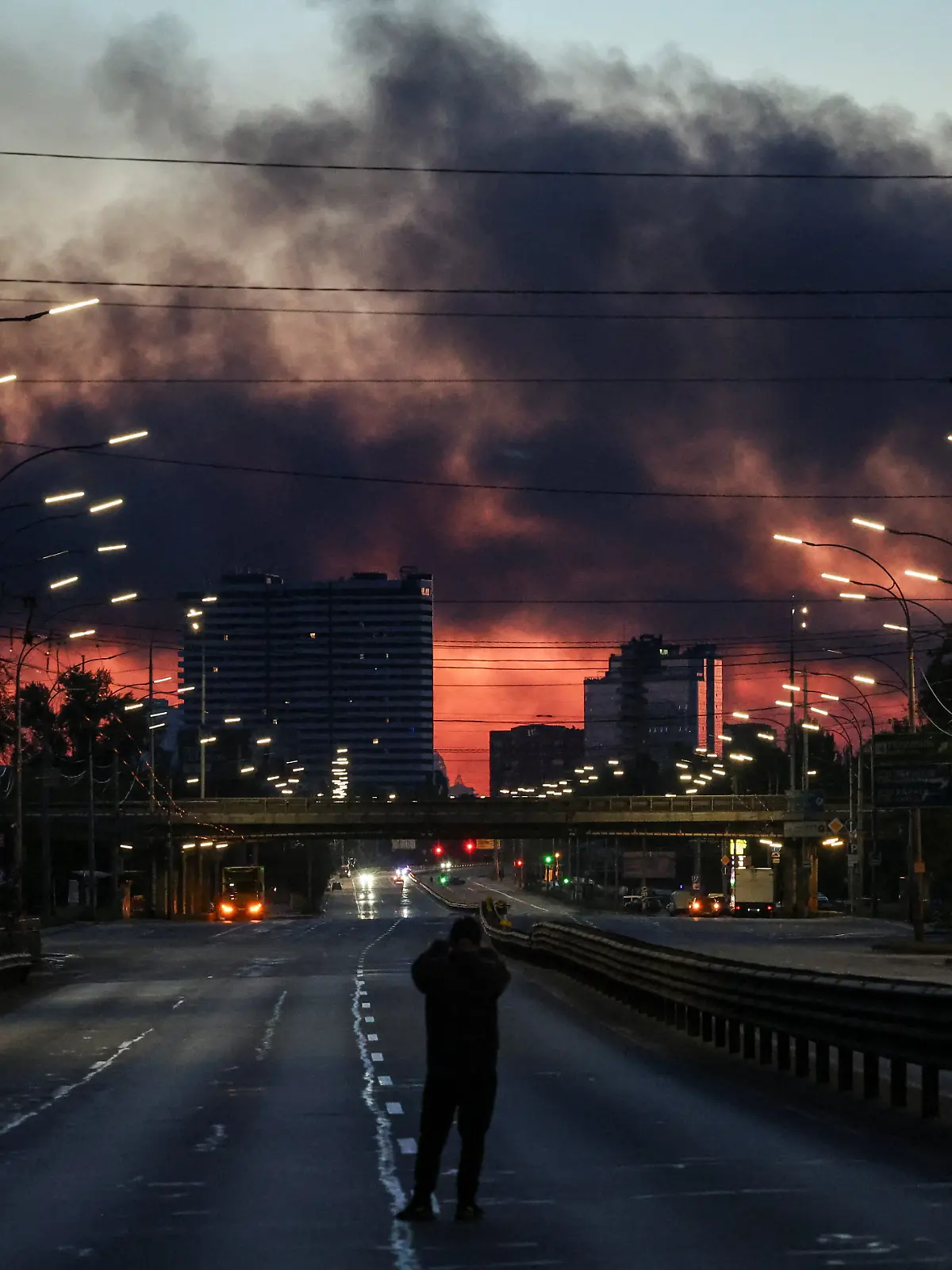 A man takes a picture of a street as smoke rises in the background after an overnight Russian missile and drone strike, amid Russia's attack on Ukraine, in Kyiv, Ukraine June 2, 2026. REUTERS/Alina Smutko TPX IMAGES OF THE DAY