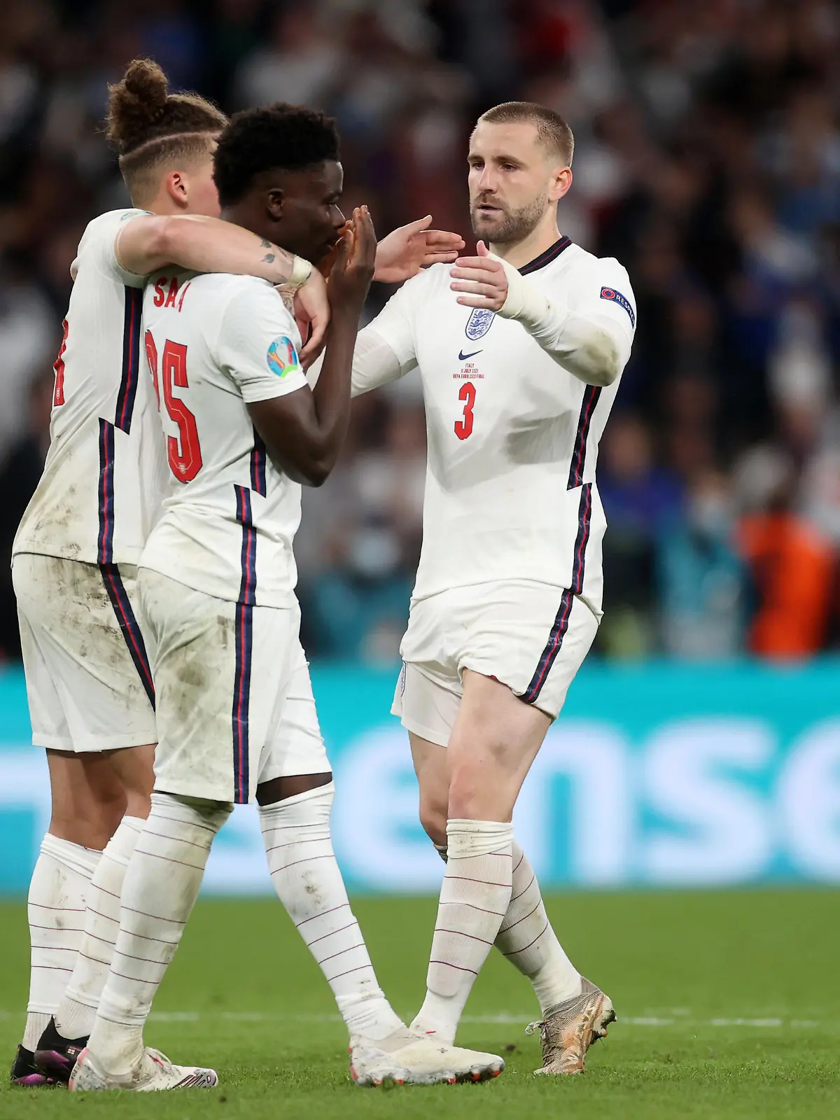 LONDON, ENGLAND - JULY 11: Bukayo Saka of England is consoled by teammates Kalvin Phillips and Luke Shaw after having their team's fifth penalty saved in a penalty shoot out during the UEFA Euro 2020 Championship Final between Italy and England at Wembley Stadium on July 11, 2021 in London, England. (Photo by Carl Recine - Pool/Getty Images)