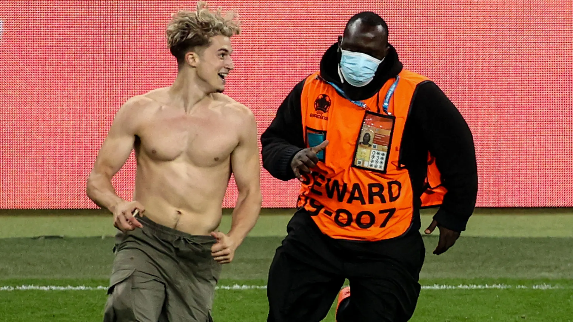 11.07.2021, Großbritannien, London: Fußball: EM, Italien - England, Finalrunde, Finale im Wembley-Stadion. Ein ORdner verfolgt eine Flitzer mit freiem Oberkörper. Foto: Christian Charisius/dpa +++ dpa-Bildfunk +++