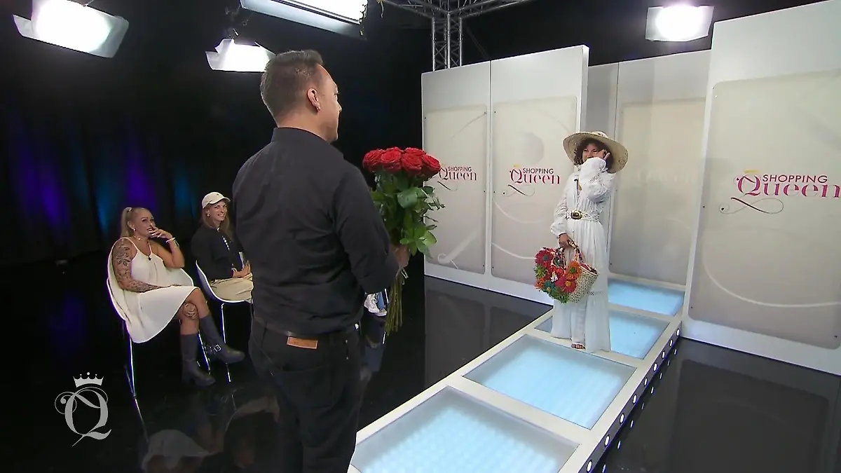 Benny steht mit einem Strauß Rosen vor Galina auf dem Laufsteg.