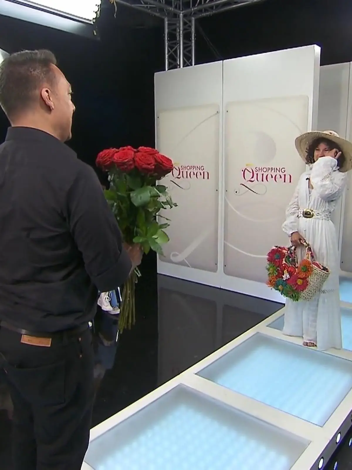 Benny steht mit einem Strauß Rosen vor Galina auf dem Laufsteg.