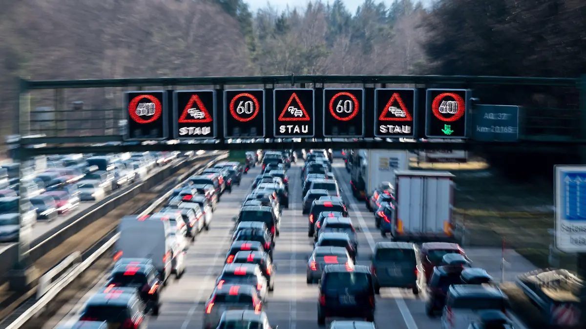 ARCHIV - 08.02.2020, Bayern, Sauerlach: Dichter Verkehr schiebt sich über die Autobahn 8 in Fahrtrichtung Salzburg und Brenner-Autobahn im Hofoldinger Forst, während über der Straße auf einer digitalen Anzeige vor Stau gewarnt wird.     (zu dpa "ADAC-Tourismuspräsident: Zeitkorridor für Sommerferien ausweiten") Foto: Matthias Balk/dpa +++ dpa-Bildfunk +++