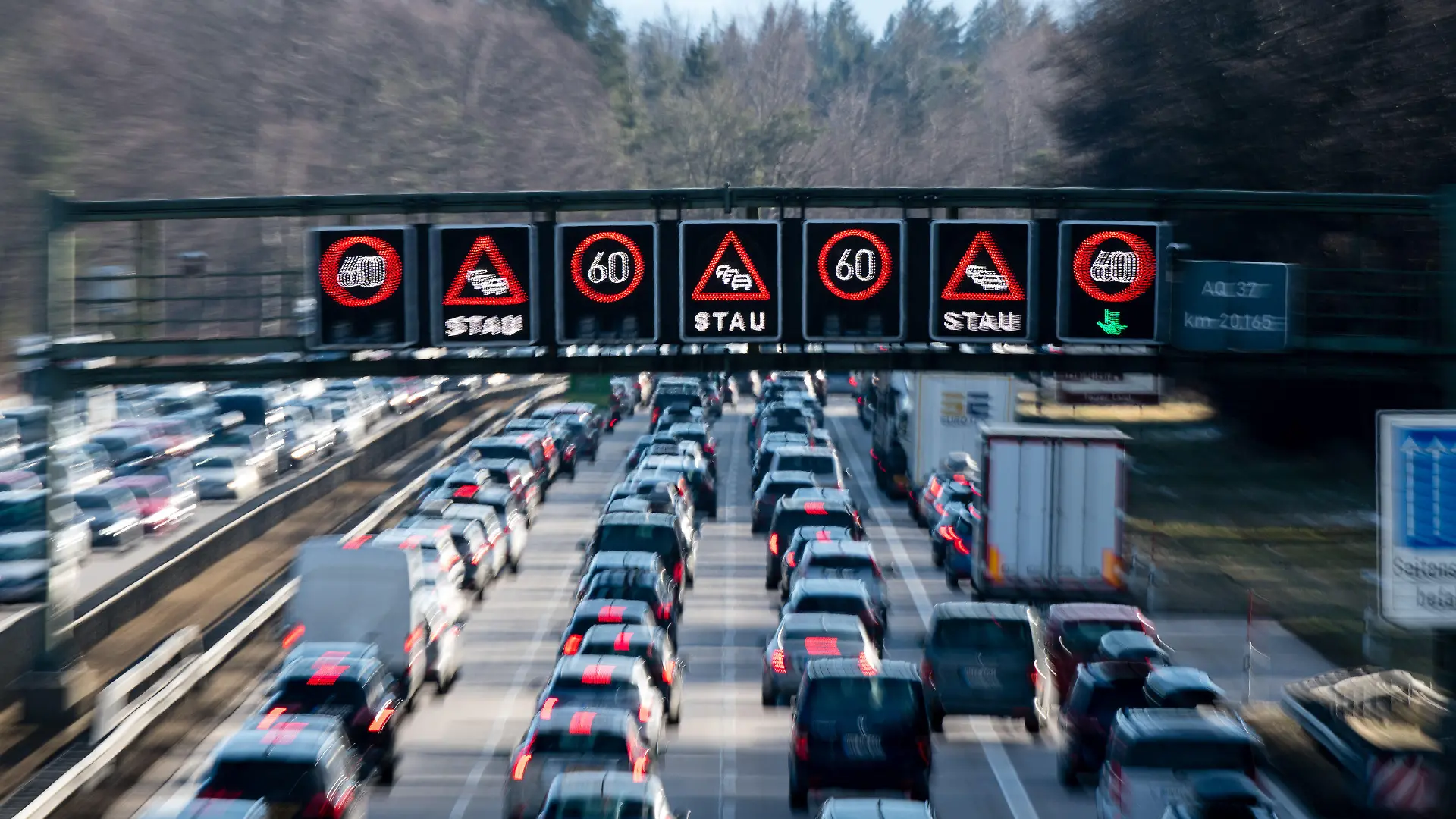 ARCHIV - 08.02.2020, Bayern, Sauerlach: Dichter Verkehr schiebt sich über die Autobahn 8 in Fahrtrichtung Salzburg und Brenner-Autobahn im Hofoldinger Forst, während über der Straße auf einer digitalen Anzeige vor Stau gewarnt wird. (zu dpa "ADAC-Tourismuspräsident: Zeitkorridor für Sommerferien ausweiten") Foto: Matthias Balk/dpa +++ dpa-Bildfunk +++