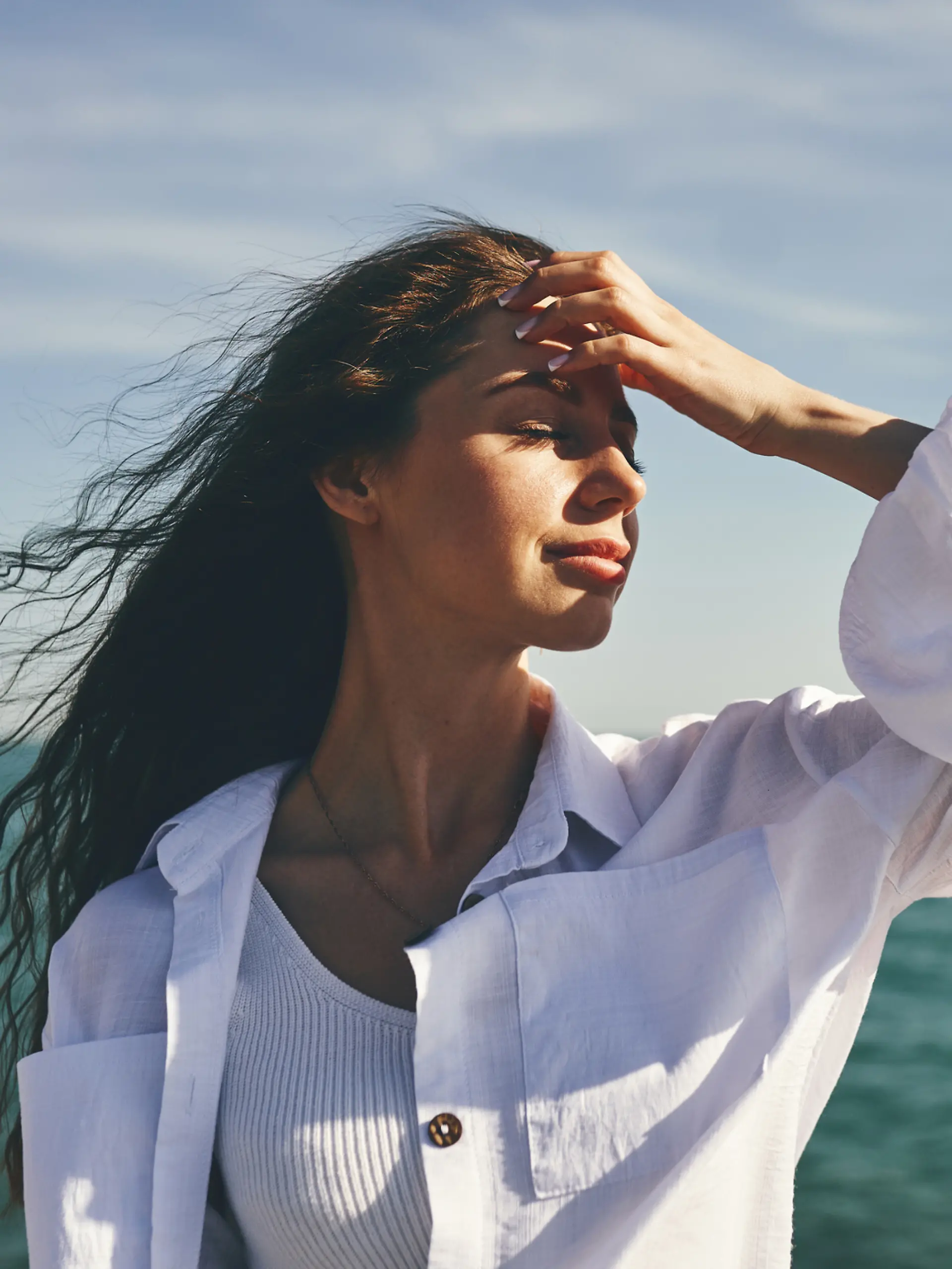 Eine Frau mit Beach Waves steht mit dem Rücken zum Meer.