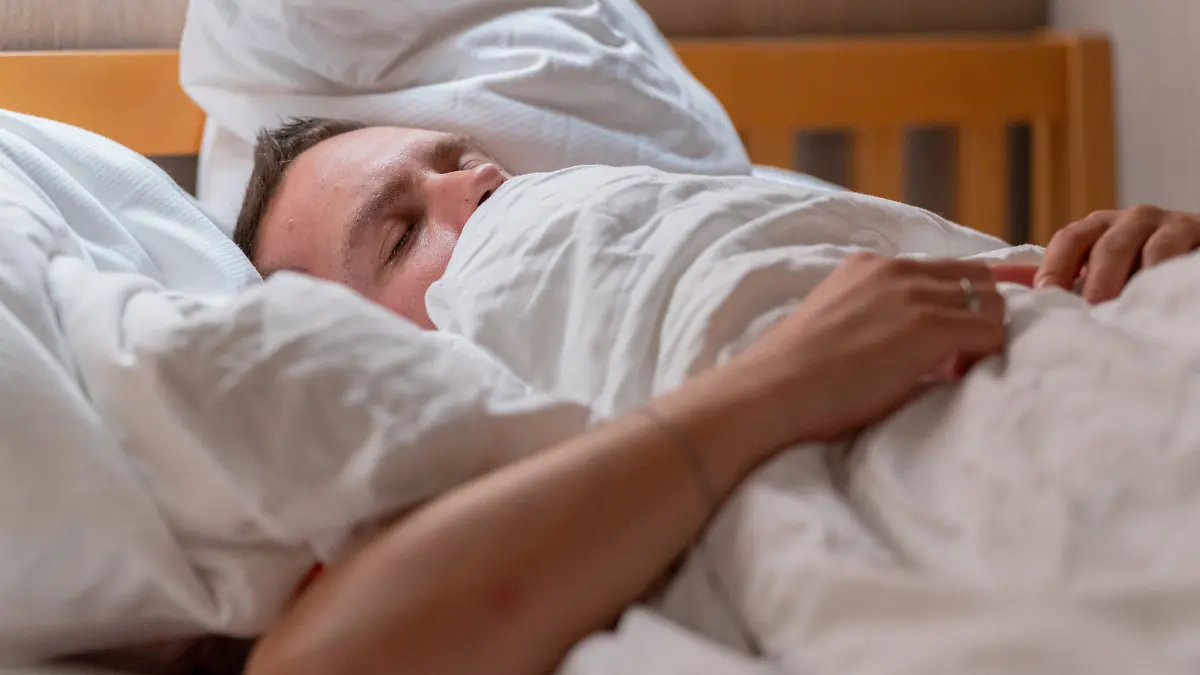 Germany - 20 September 2025: A man lies cuddled up in bed under a blanket and sleeps peacefully, symbolizing rest, relaxation and restful sleep in everyday life *** Ein Mann liegt im Bett eingekuschelt unter einer Decke und schläft friedlich, was Ruhe, Entspannung und erholsamen Schlaf im Alltag symbolisiert