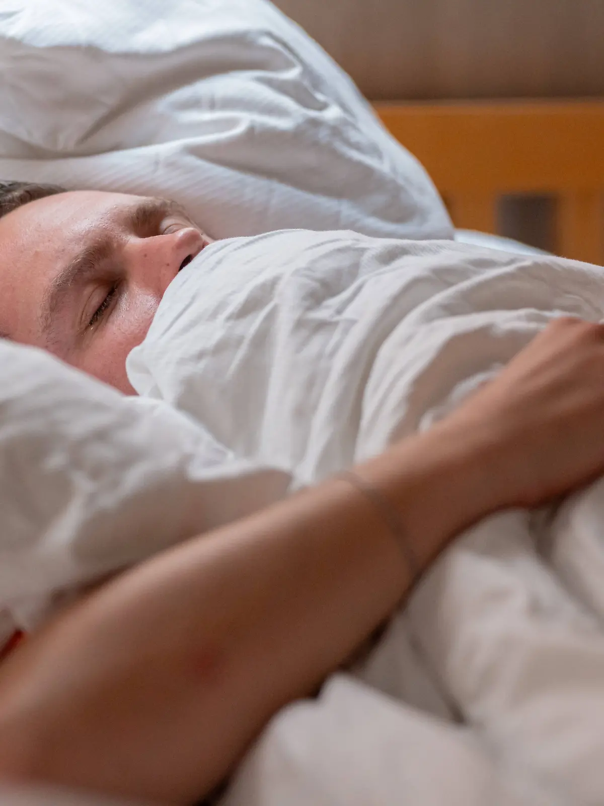 Germany - 20 September 2025: A man lies cuddled up in bed under a blanket and sleeps peacefully, symbolizing rest, relaxation and restful sleep in everyday life *** Ein Mann liegt im Bett eingekuschelt unter einer Decke und schläft friedlich, was Ruhe, Entspannung und erholsamen Schlaf im Alltag symbolisiert