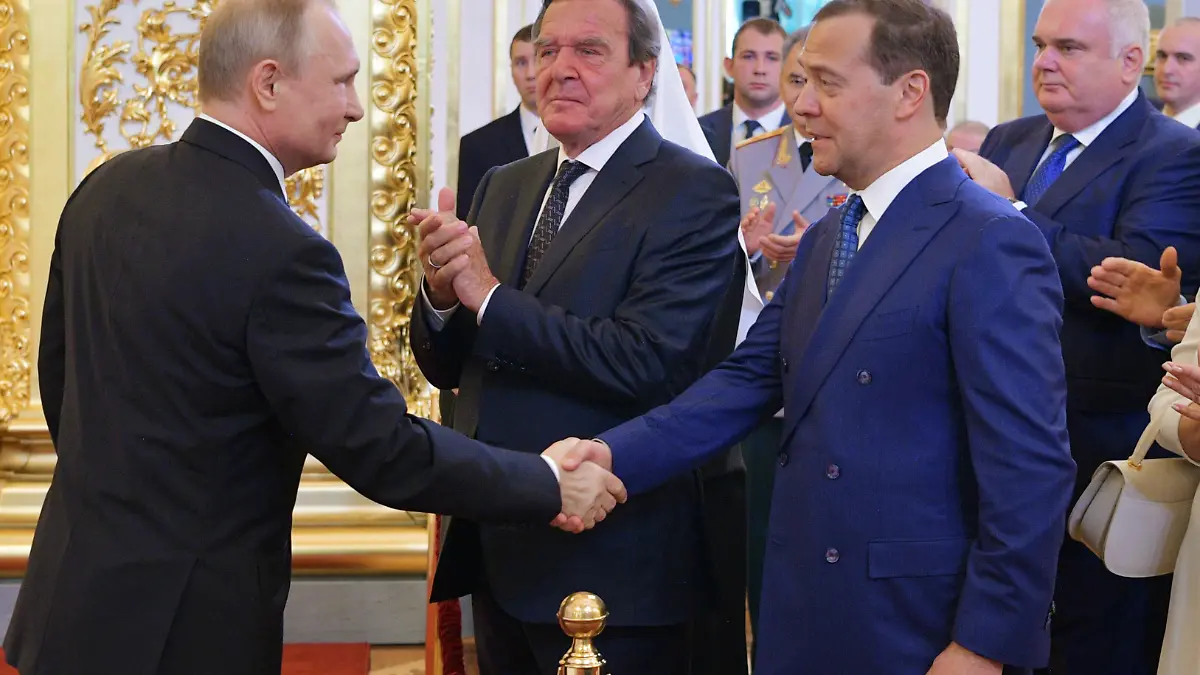 07.05.2018, Russland, Moskau: Wladimir Putin (l), Präsident von Russland, gibt während seiner Amtseinführung als Präsident von Russland Dimitri Medwedew (2.v.r), Ministerpräsident von Russland, die Hand. Der frühere deutsche Bundeskanzler Gerhard Schröder steht zwischen den beiden. Der russische Präsident Wladimir Putin hat am Montag den Eid für eine vierte Amtszeit abgelegt. Foto: Alexei Druzhinin/POOL SPUTNIK KREMLIN/AP/dpa +++ dpa-Bildfunk +++