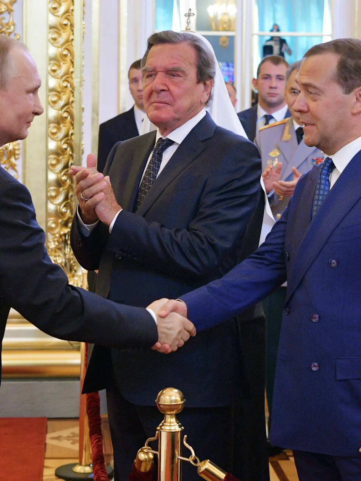 07.05.2018, Russland, Moskau: Wladimir Putin (l), Präsident von Russland, gibt während seiner Amtseinführung als Präsident von Russland Dimitri Medwedew (2.v.r), Ministerpräsident von Russland, die Hand. Der frühere deutsche Bundeskanzler Gerhard Schröder steht zwischen den beiden. Der russische Präsident Wladimir Putin hat am Montag den Eid für eine vierte Amtszeit abgelegt. Foto: Alexei Druzhinin/POOL SPUTNIK KREMLIN/AP/dpa +++ dpa-Bildfunk +++