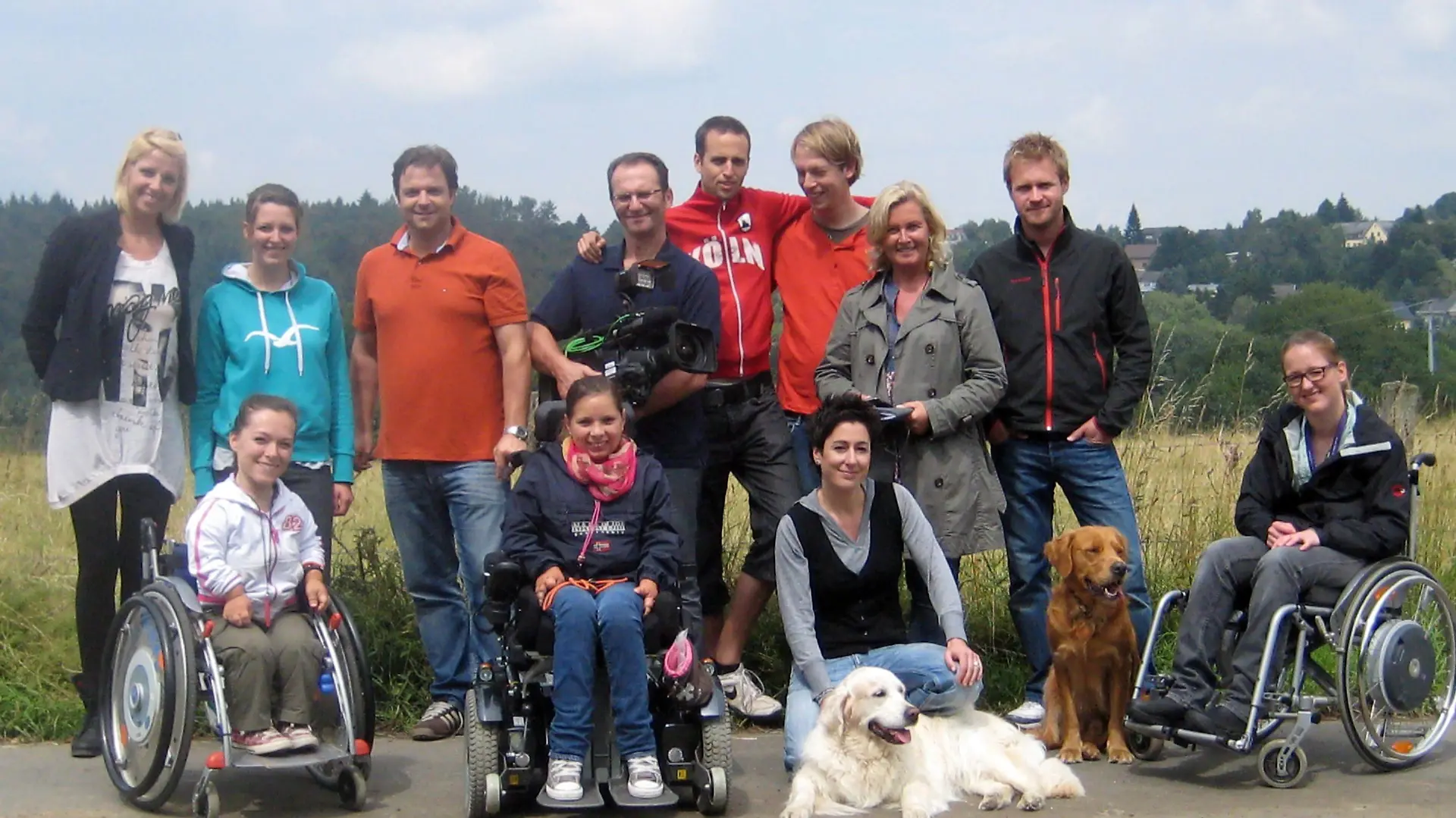 Das VITA -Assistenzhunde-Team: Hintere Reihe v.l.: Sonja Heinekind, Meike Windgassen, Martin Rütter, Klaus Grittner, Markus Gummersbach, Philipp Lott, Elisabeth Neumann, Thomas Kita. Vordere Reihe v.l.: Dominique Kogut, Pauline Bader, Hund "Eve" (weiß), Dunja Hayali, Hund "Homer" (braun), Johanna Houben.