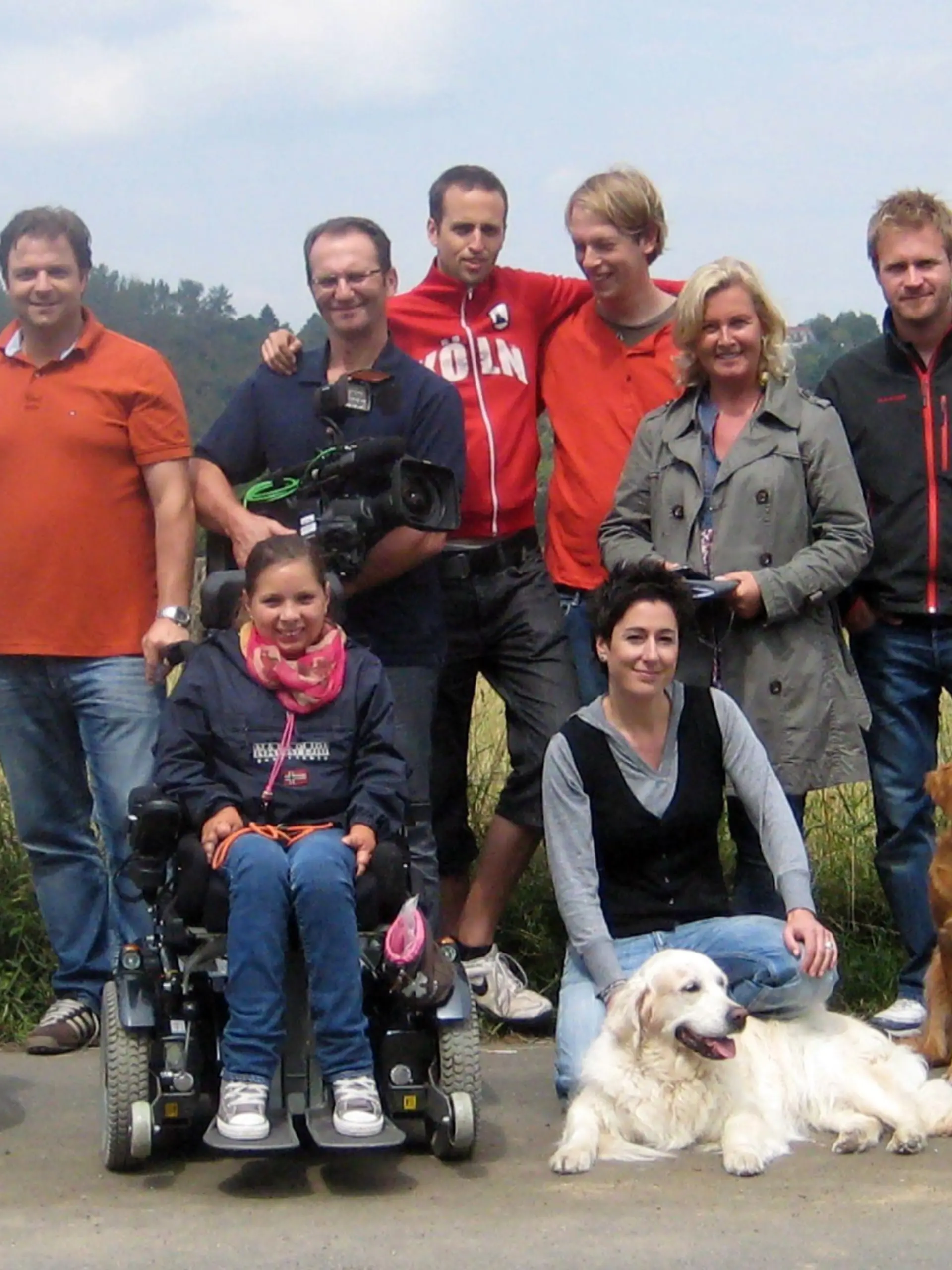 Das VITA -Assistenzhunde-Team: Hintere Reihe v.l.: Sonja Heinekind, Meike Windgassen, Martin Rütter, Klaus Grittner, Markus Gummersbach, Philipp Lott, Elisabeth Neumann, Thomas Kita. Vordere Reihe v.l.: Dominique Kogut, Pauline Bader, Hund "Eve" (weiß), Dunja Hayali, Hund "Homer" (braun), Johanna Houben.