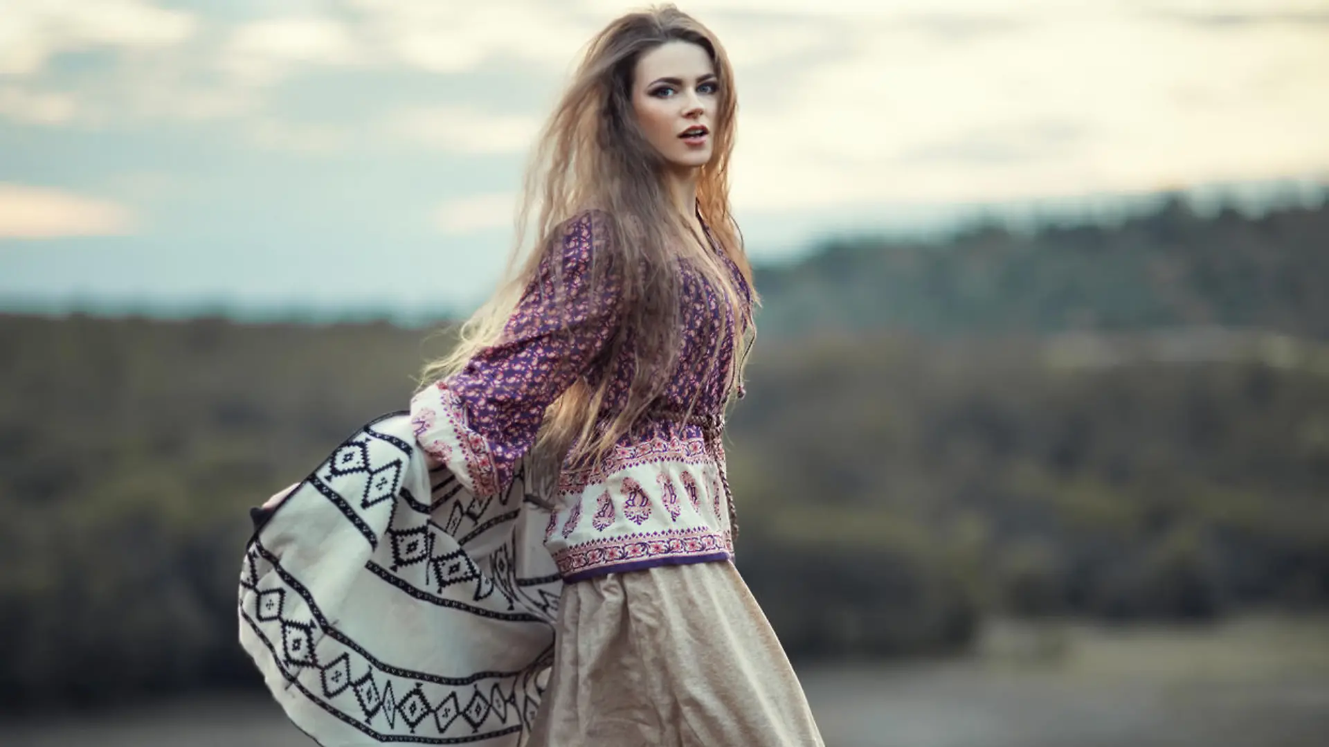Beautiful hippie girl jumping outdoors at sunset. Boho fashion style