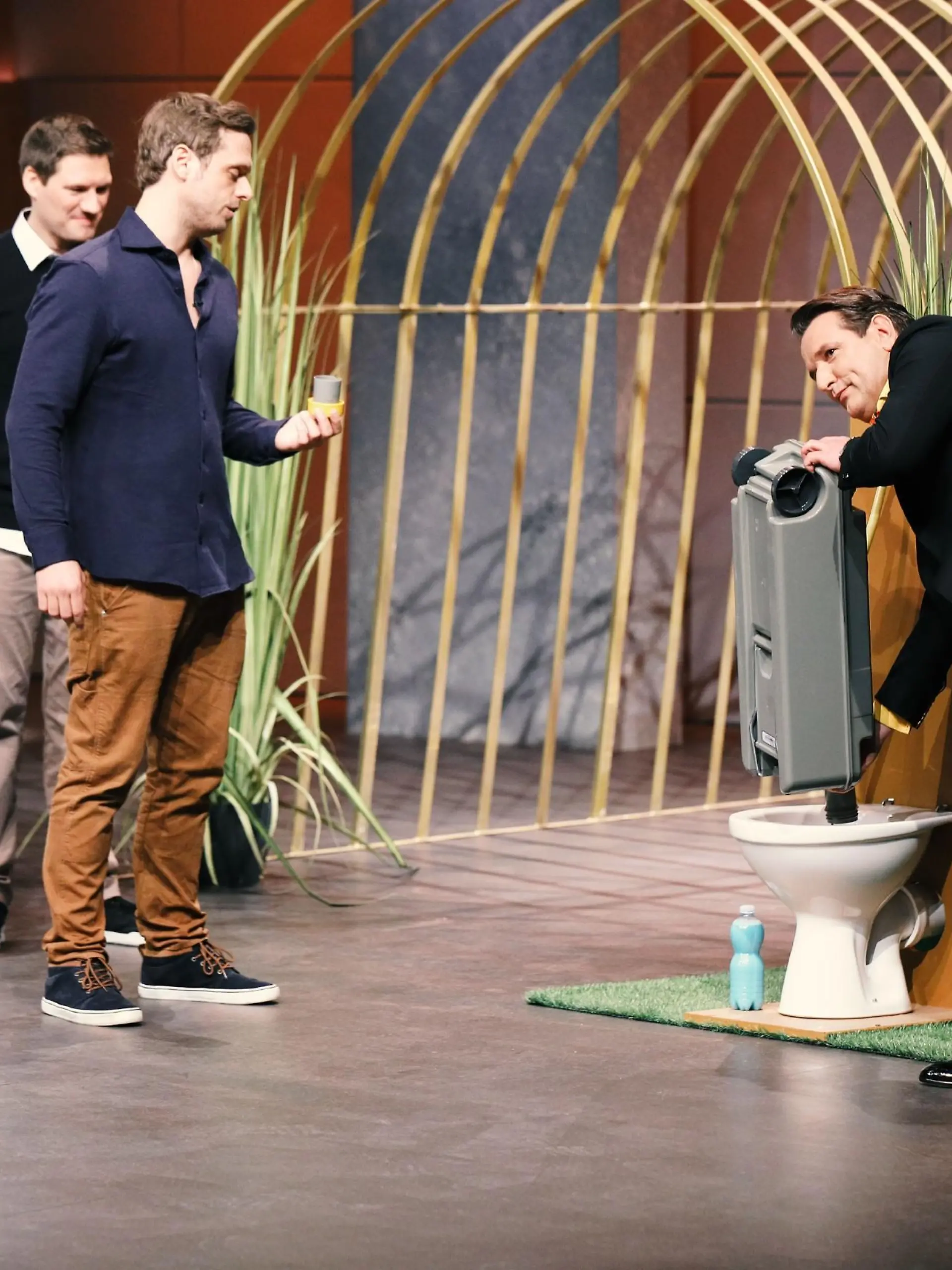 Dr. Simon Freutel (M.) und Ralf Winkelmann (l.) aus Düsseldorf präsentieren mit "Camping Butler" einen Vollautomaten zur Reinigung von Camping-Toiletten-Kassetten. Investor Ralf Dümmel nimmt das Produkt genau unter die Lupe.