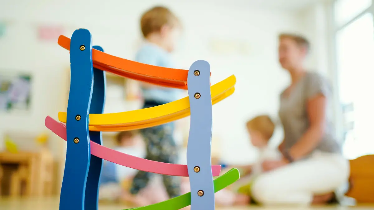 ARCHIV - 29.06.2020, Baden-Württemberg, Schriesheim: Eine Erzieherin spielt in einer Kindertagesstätte hinter einer Rollbahn mit Kindern. (zu dpa «Umfrage: Überlastung bei Kita-Personal, Unterforderung bei Kindern») Foto: Uwe Anspach/dpa +++ dpa-Bildfunk +++