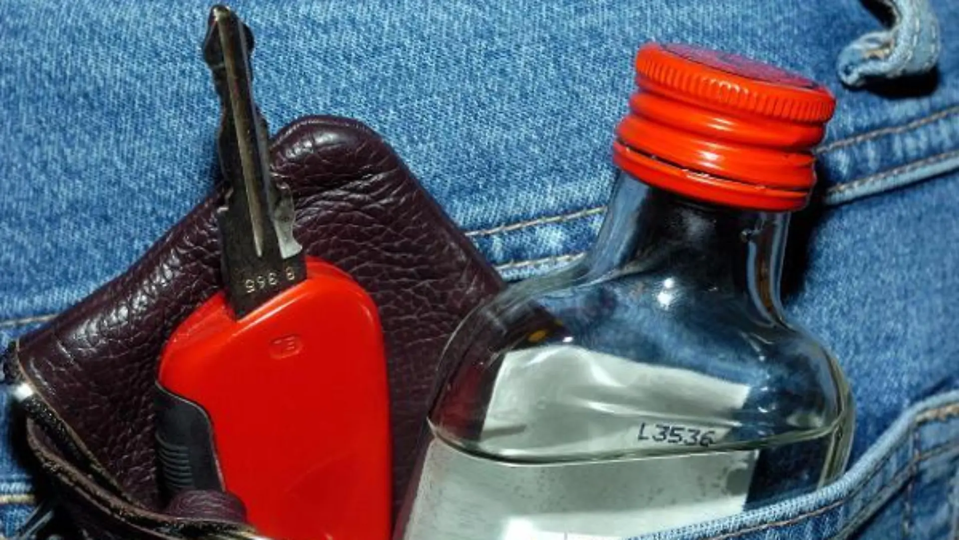 In der Tasche einer Jeans-Hose stecken ein Autoschlüssel und ein "Flachmann" eine kleine Flasche mit Alkohol, gestelltes Symbolfoto zum Thema Fahren unter Alkoholeinfluss, aufgenommen am 14.02.2007. In der Statistik der Unfallursachen rangiert das Fahren unter Einfluss von Alkohol ganz vorn, angeführt von jugendlichen Fahranfängern. Aus diesem Grunde strebt die deutsche Regierung ein absolutes Alkohol-Verbot für Führerschein-Neulinge an, wenn sich diese ans Steuer setzen. Das Kabinett beschloss am 14.02.2007 in Berlin, dass dies während einer zweijährigen Probezeit gelten soll. Foto: Hans Wiedl +++(c) dpa - Report+++