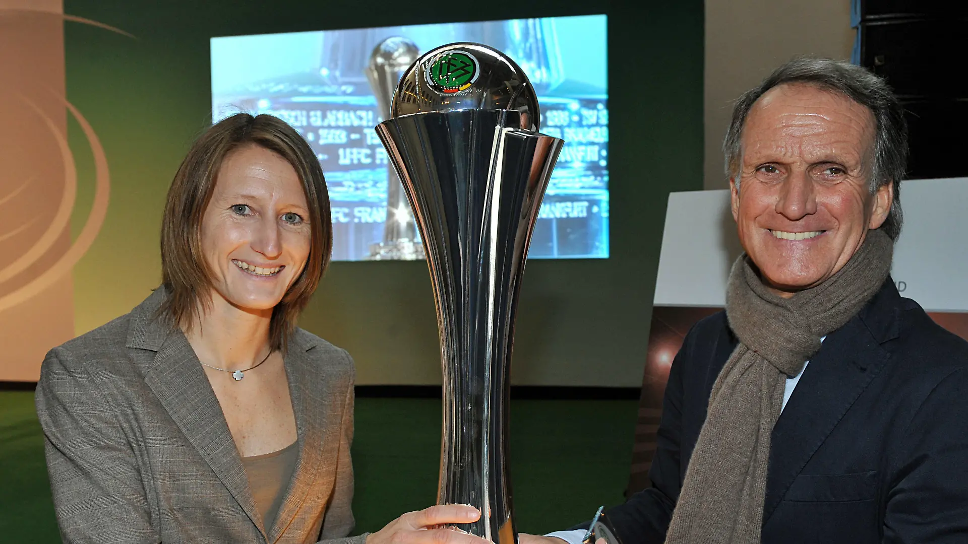Die Fußballnationalspielerin Sonja Fuss (l) und Fußball-Legende Wolfgang Overath posieren mit dem neuen DFB-Pokal der Frauen am Dienstag (08.12.2009) im Kölner Rathaus. Am 15. Mai 2010 findet erstmals das Endspiel im DFB-Pokal der Frauen im RheinEnergieStadion in Köln statt. Dafür wurde auch ein neuer Pokal erstellt. Die Trophäe, die von Thomas Hug von der Design Agentur Hug & Dofmüller aus Luzern kreiert wurde, ist 60 Zentimeter hoch, 11 Kilogramm schwer und steht auf einem abgestuften Sockel, der alle Namen der bisherigen Pokalsieger der Frauen trägt. Foto: Jörg Carstensen dpa/lnw +++(c) dpa - Bildfunk+++
