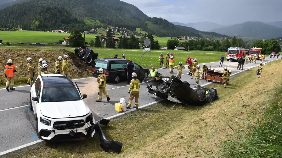 11.07.2021, Österreich, Achenkirch: Helfer stehen nach einem schweren Unfall bei Achenkirch an einer Straße nahe der Grenze zu Deutschland. Bei dem Unfall mit drei Fahrzeugen im österreichischen Bundesland Tirol sind fünf Menschen zum Teil schwer verletzt worden. Die Unfallopfer stammen aus Bayern und aus der Gegend um Marburg in Hessen. Foto: Jürgen Masching/-/dpa +++ dpa-Bildfunk +++