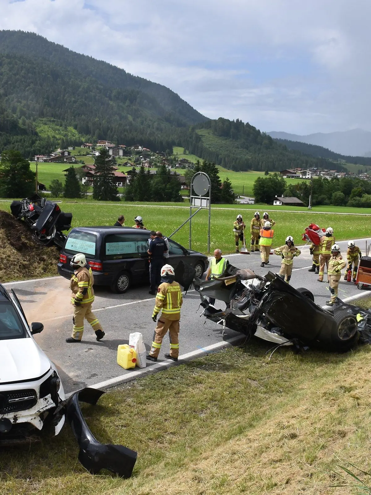 11.07.2021, Österreich, Achenkirch: Helfer stehen nach einem schweren Unfall bei Achenkirch an einer Straße nahe der Grenze zu Deutschland. Bei dem Unfall mit drei Fahrzeugen im österreichischen Bundesland Tirol sind fünf Menschen zum Teil schwer verletzt worden. Die Unfallopfer stammen aus Bayern und aus der Gegend um Marburg in Hessen. Foto: Jürgen Masching/-/dpa +++ dpa-Bildfunk +++