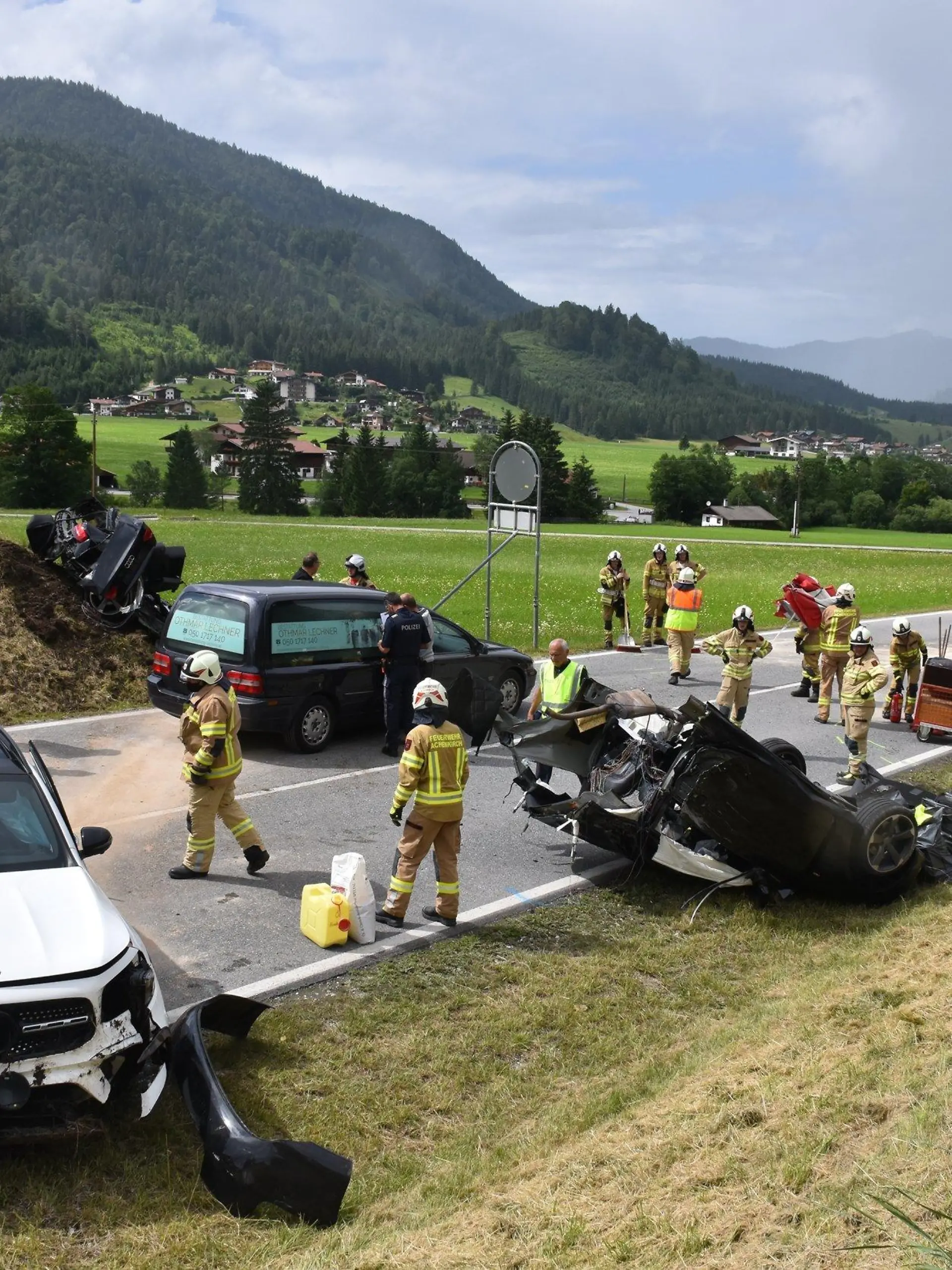 11.07.2021, Österreich, Achenkirch: Helfer stehen nach einem schweren Unfall bei Achenkirch an einer Straße nahe der Grenze zu Deutschland. Bei dem Unfall mit drei Fahrzeugen im österreichischen Bundesland Tirol sind fünf Menschen zum Teil schwer verletzt worden. Die Unfallopfer stammen aus Bayern und aus der Gegend um Marburg in Hessen. Foto: Jürgen Masching/-/dpa +++ dpa-Bildfunk +++