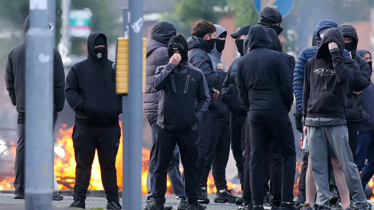 Masked youths block a road with burning debris in north Belfast, Northern Ireland, in the evening of June 9, 2026. Northern Ireland police appealed for calm Tuesday after a stabbing in Belfast allegedly by a Sudanese suspect and captured in a graphic video prompted calls for anti-immigration protests from UK far-right figures. (Photo by Paul Faith / AFP)