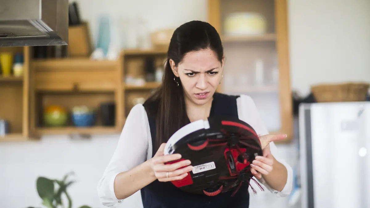 Eine Frau steht in der Küche mit einem kaputten Staubsaugerroboter