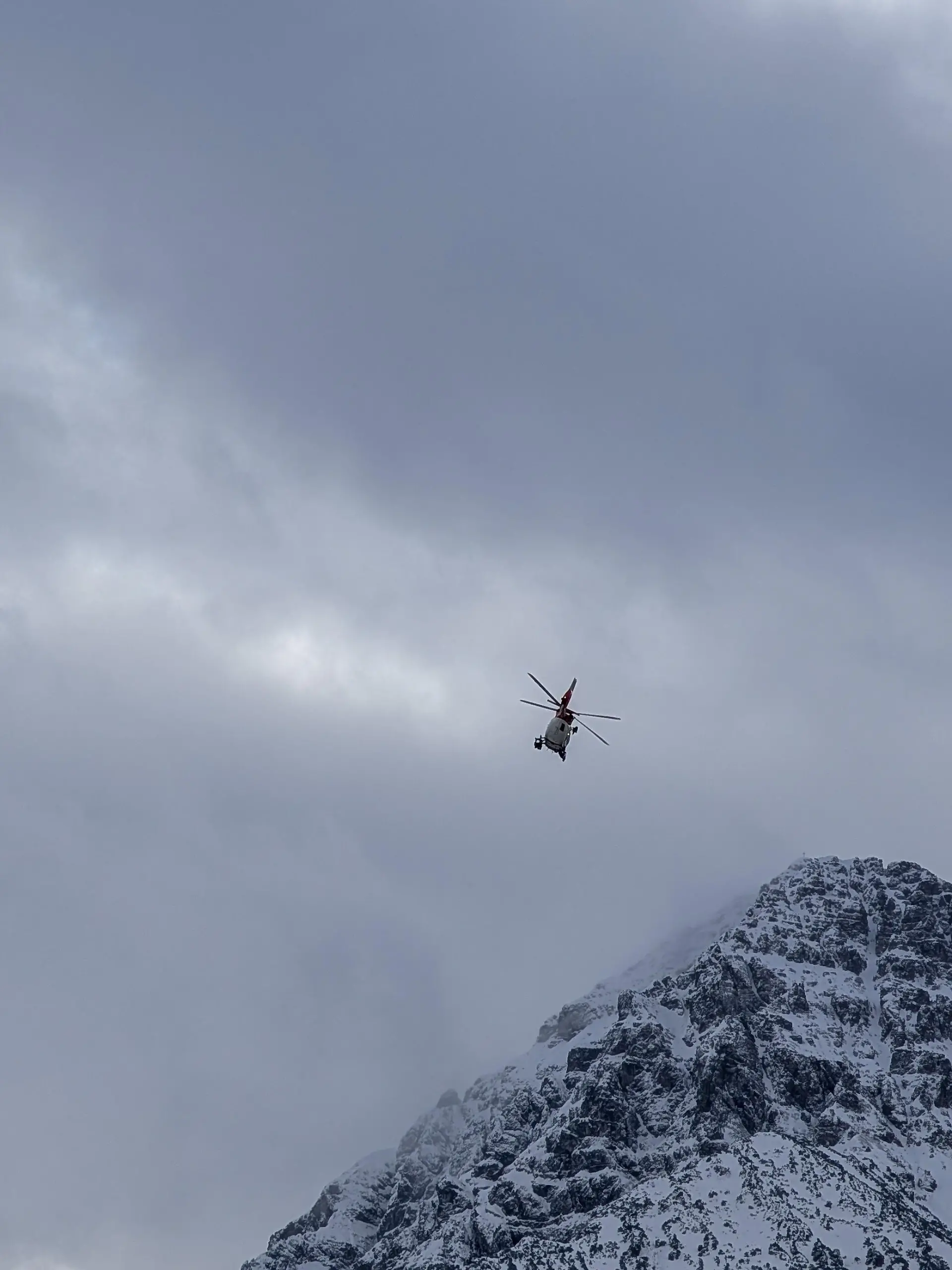 A mountain emergency rescue helicopter flies over a snow-covered mountain peak in Reutte, Tyrol, Austria, on January 3, 2026. The state-of-the-art red and white aircraft is utilized for challenging search and rescue missions in the alpine terrain of the greater Reutte area. (Photo by Michael Nguyen/NurPhoto)