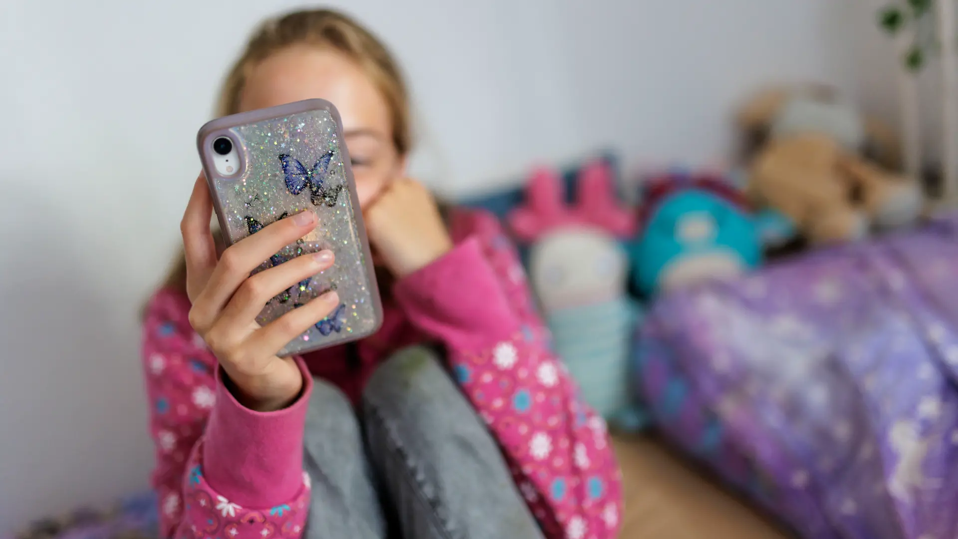 Symbolfoto zum Thema Handynutzung bei Kindern: Ein Maedchen sitzt in ihrem Bett und ist am Handy. Berlin, 22.07.2025.