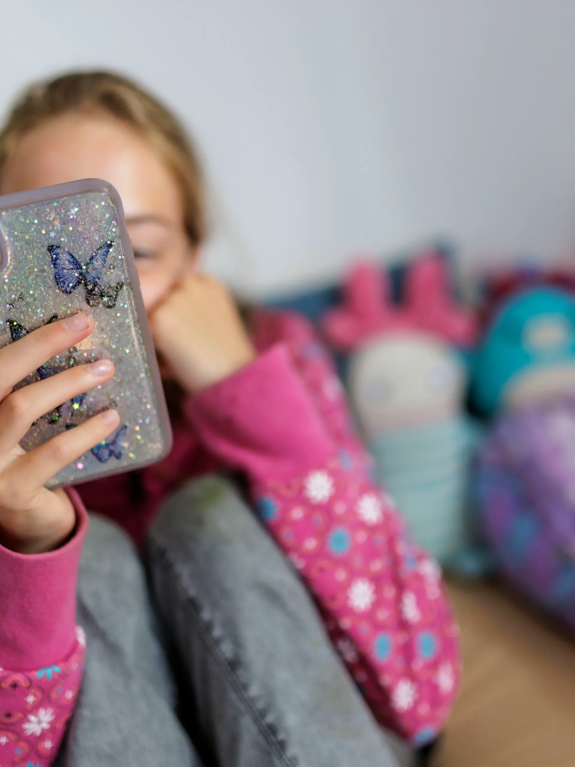 Symbolfoto zum Thema Handynutzung bei Kindern: Ein Maedchen sitzt in ihrem Bett und ist am Handy. Berlin, 22.07.2025.