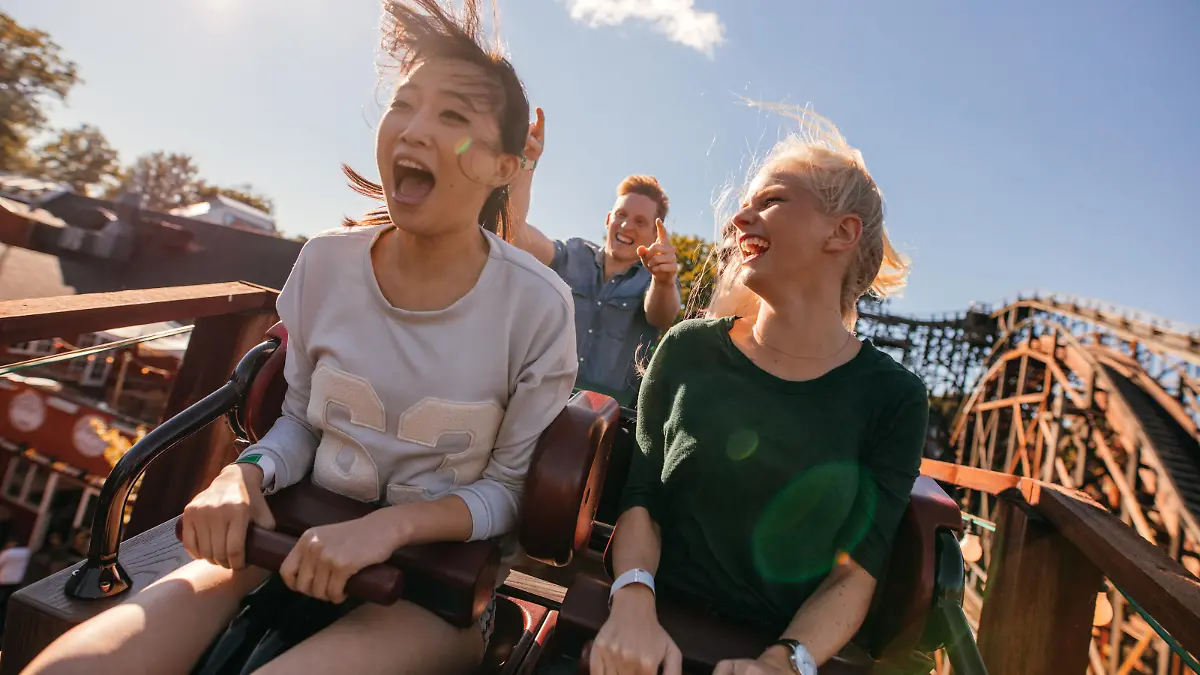 Zwei junge Frauen, vermutlich Freundinnen, haben Spaß auf ihrer Achterbahnfahrt.