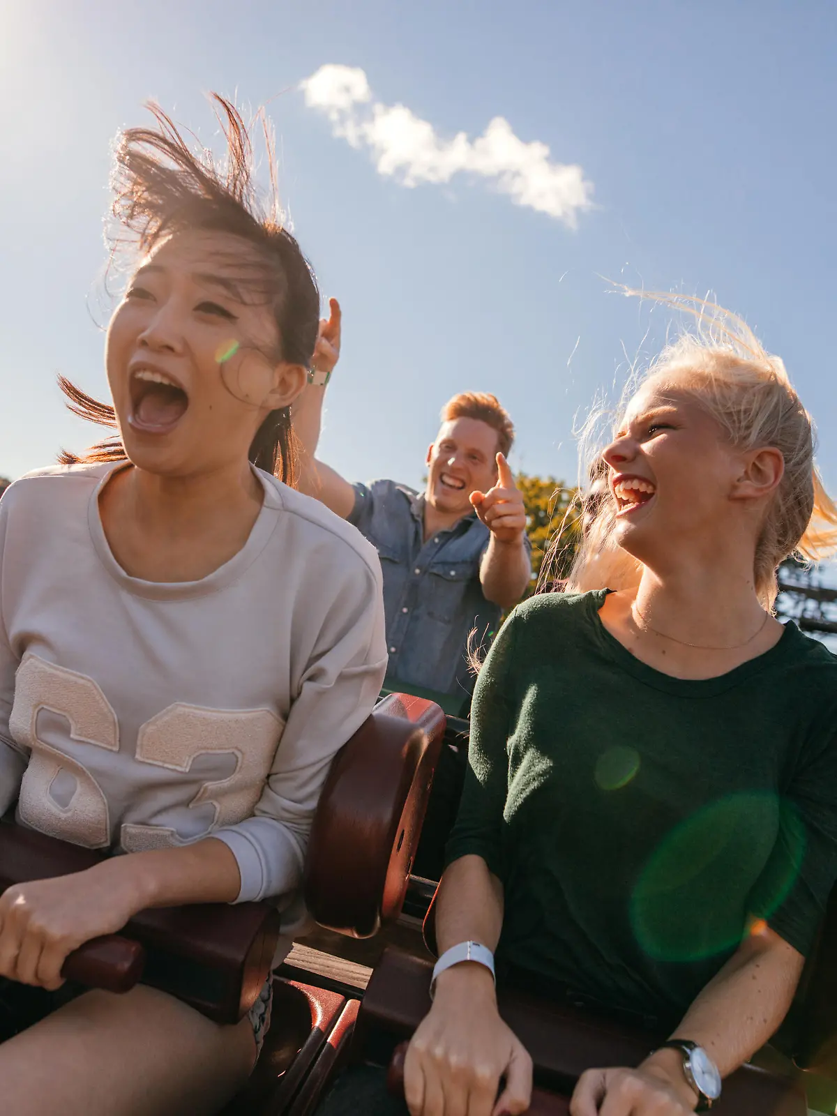 Zwei junge Frauen, vermutlich Freundinnen, haben Spaß auf ihrer Achterbahnfahrt.