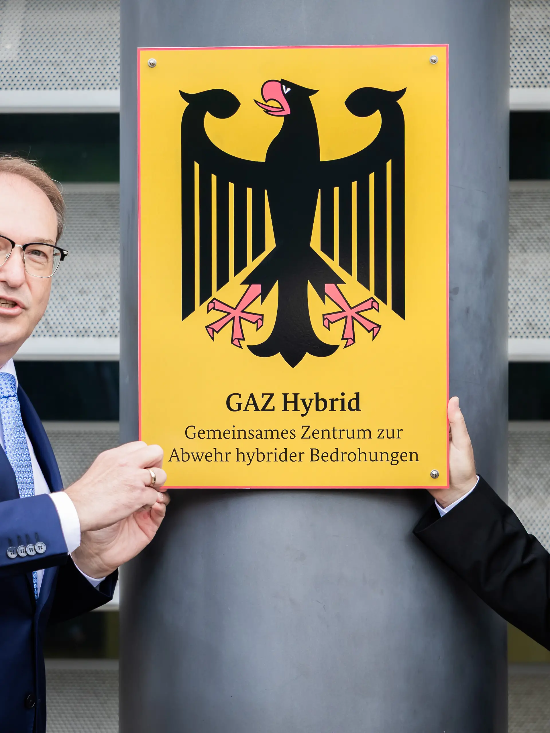 Alexander Dobrindt (CSU, l), Bundesinnenminister, schraubt im Beisein von Sinan Selen, Präsident des Bundesamtes für Verfassungsschutz, symbolisch bei der Einweihung des Gemeinsamen Zentrums zur Abwehr hybrider Bedrohungen (GAZ Hybrid) das entsprechende Schild an. Das neue Abwehrzentrum wird in Räumlichkeiten des Bundesamtes für Verfassungsschutz in Berlin-Treptow angesiedelt sein.