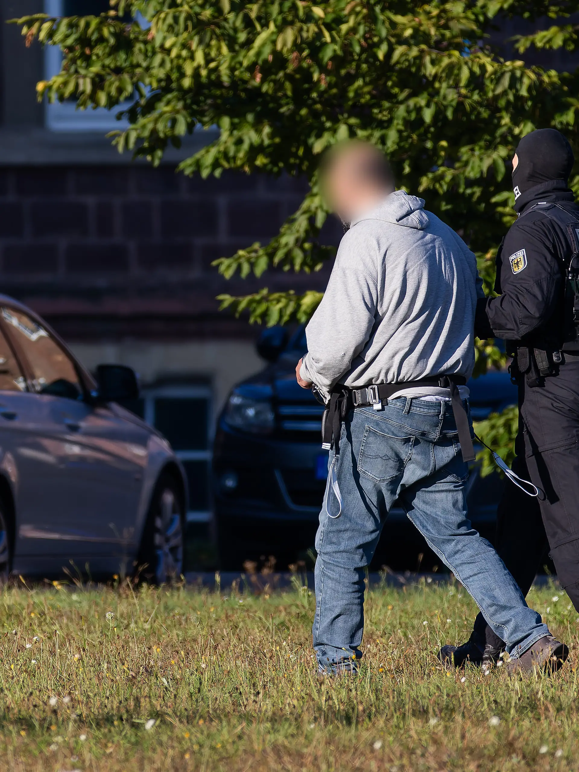 Ein Mann wird von einem Bundespolizisten von einem Helikopter (nicht im Bild) zu einem Fahrzeug der Bundespolizei geführt. Der Generalbundesanwalt hat gestern drei mutmaßliche Mitglieder der islamistischen Terrororganisation Hamas festnehmen lassen. Die Männer werden heute in Karlsruhe beim Ermittlungsrichter des BGH vorgeführt.
