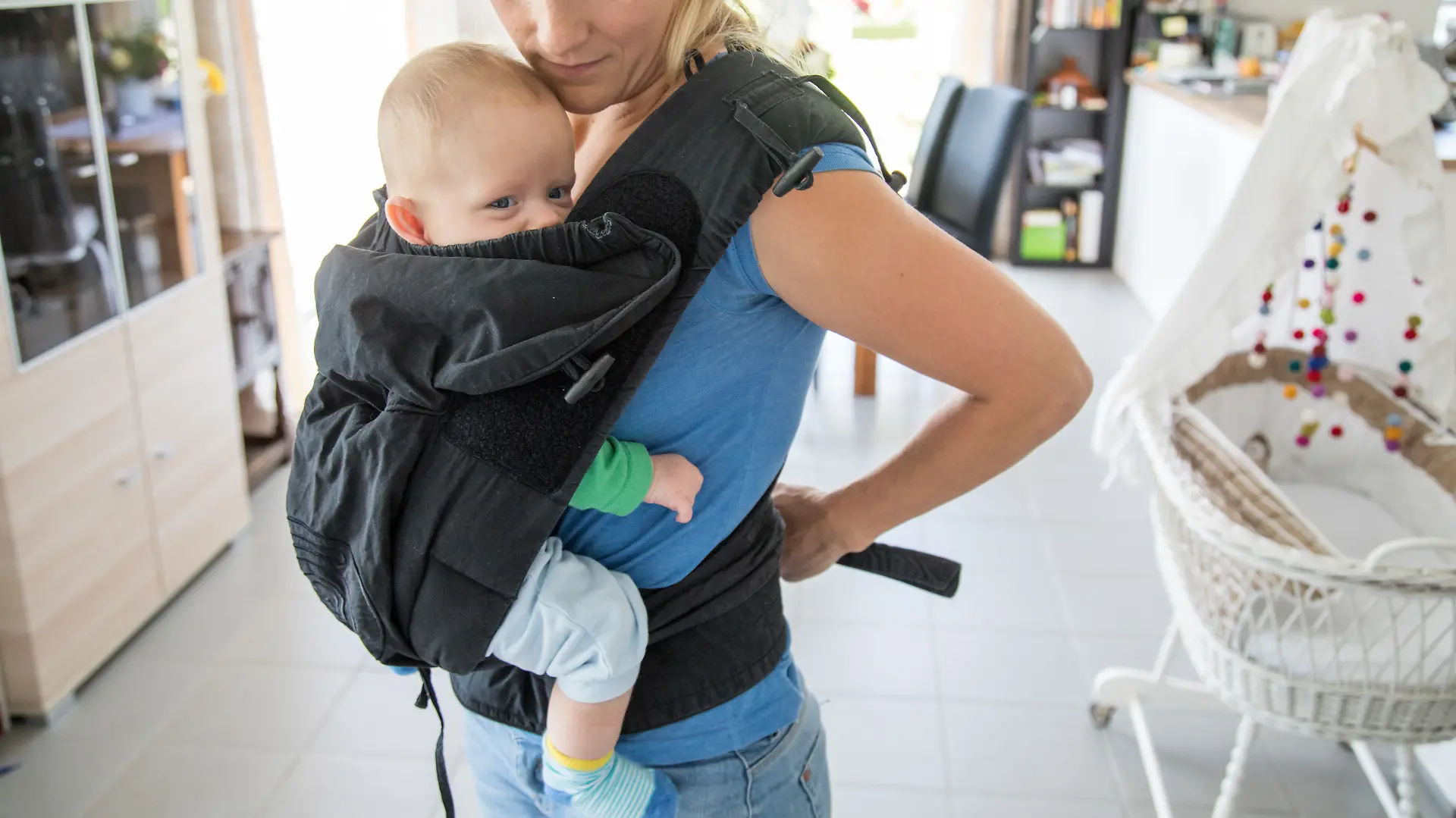Eine Frau schnallt sich ihr Kind in einer Babytrage um (Symbolbild)