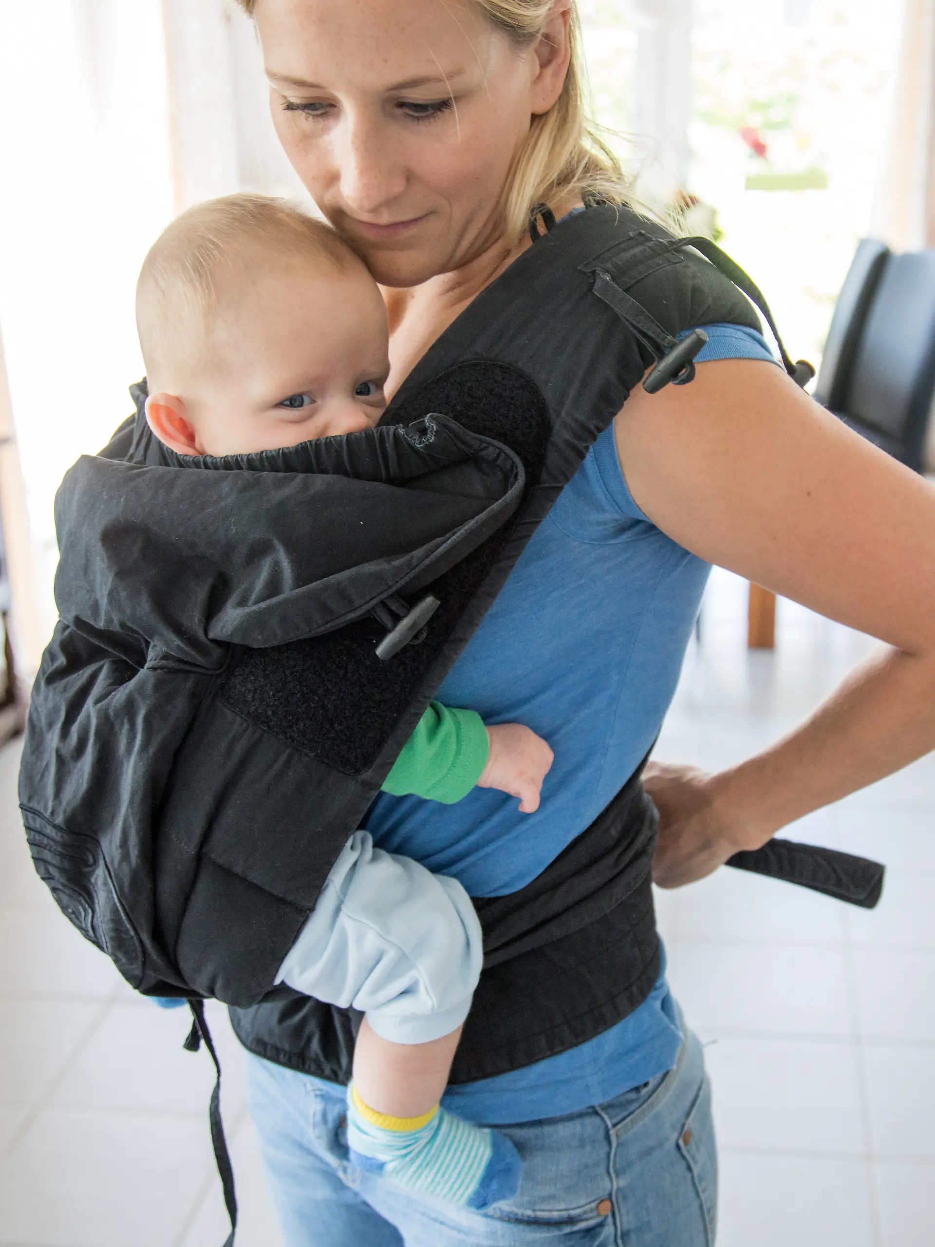 Eine Frau schnallt sich ihr Kind in einer Babytrage um (Symbolbild)