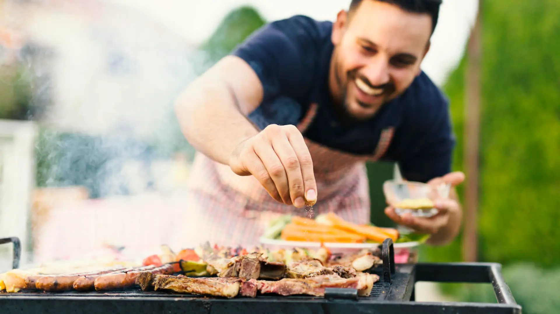 Mann grillt im Garten Fleisch