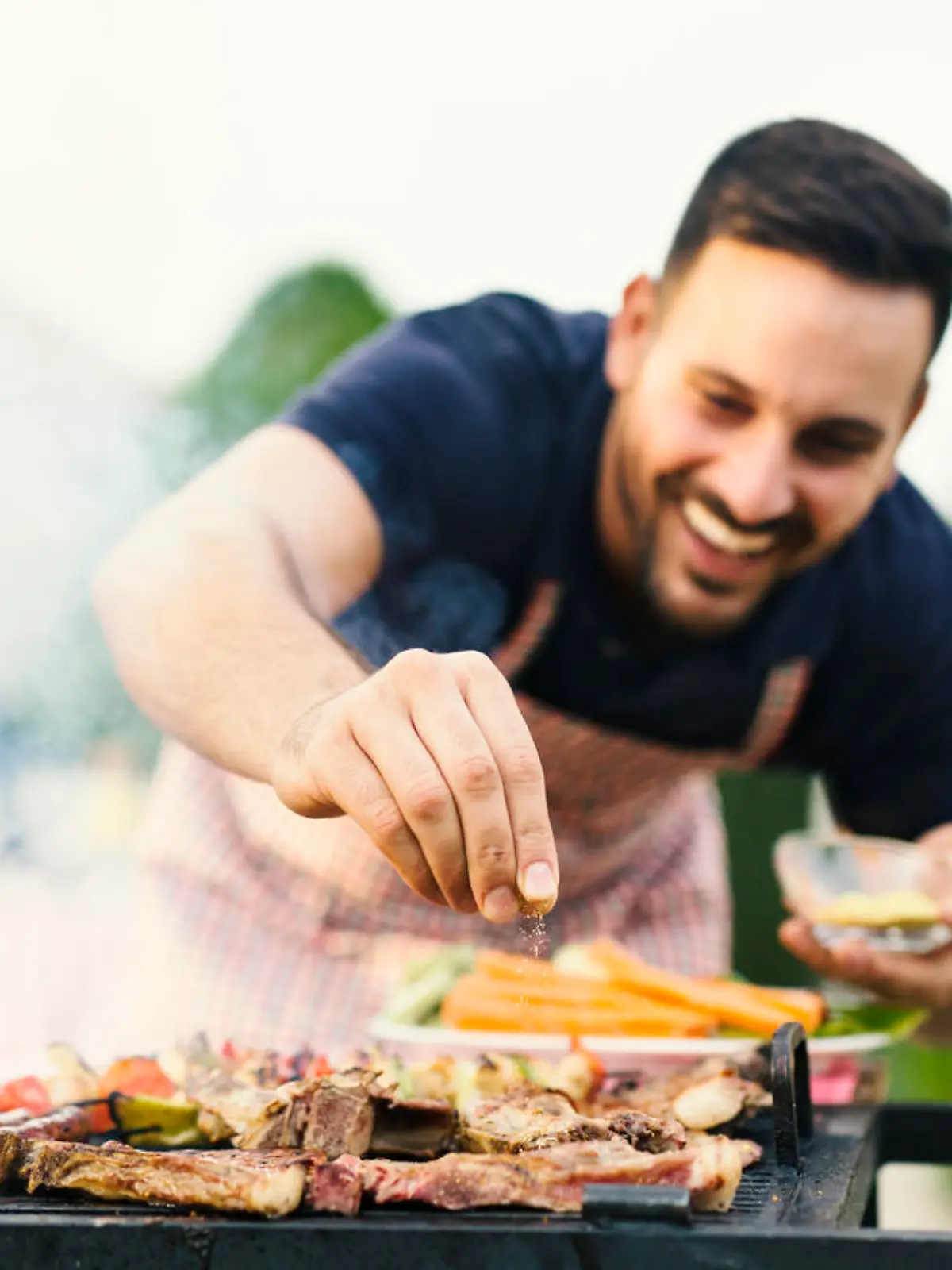 Mann grillt im Garten Fleisch