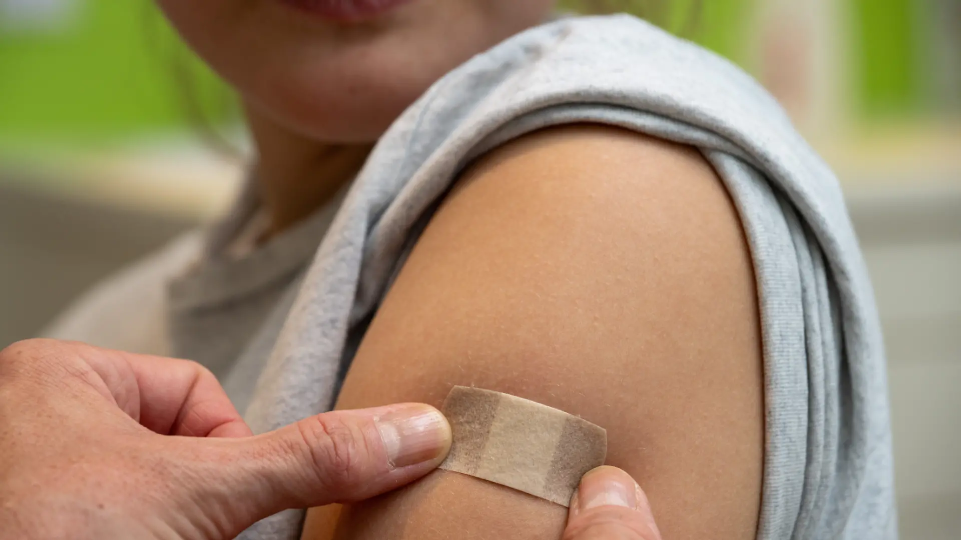 Gynäkologin Stephanie Eder versorgt an Patientin Clara nach der HPV-Impfung in einer Frauenarztpraxis die Injektionsstelle. Empfohlen ist die HPV-Impfung von der STIKO ab dem Alter von 9 Jahren. Ist die Impfung nicht bis zum Alter von 14 Jahren erfolgt, empfiehlt die STIKO, diese noch bis zum Alter von 17 Jahren nachzuholen.