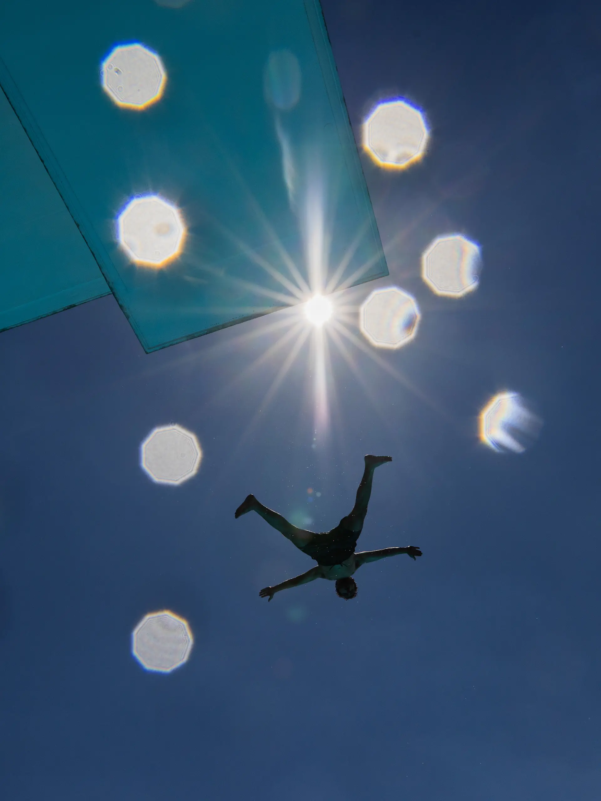 Ein Mensch springt bei hohen Temperaturen und Sonne im Stadionbad vom Sprungturm. +++ dpa-Bildfunk +++
