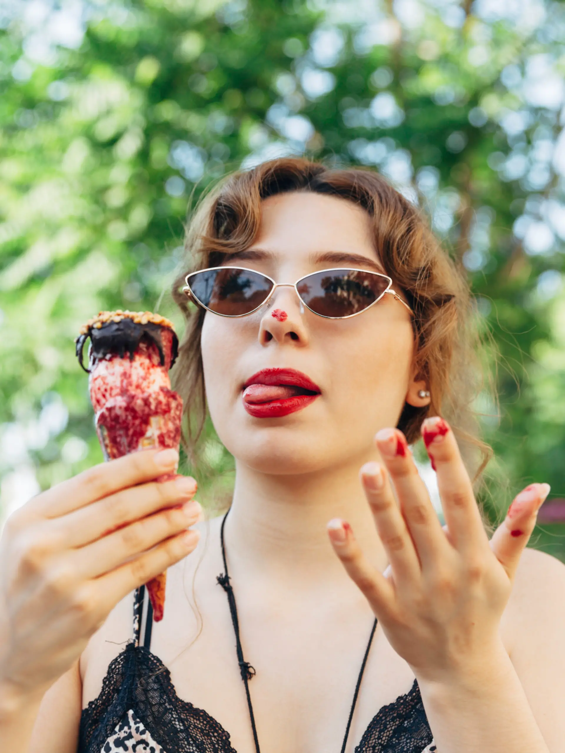 Junge Frau mit Sonnenbrille versucht, ihr schmelzendes Eis schnell zu essen