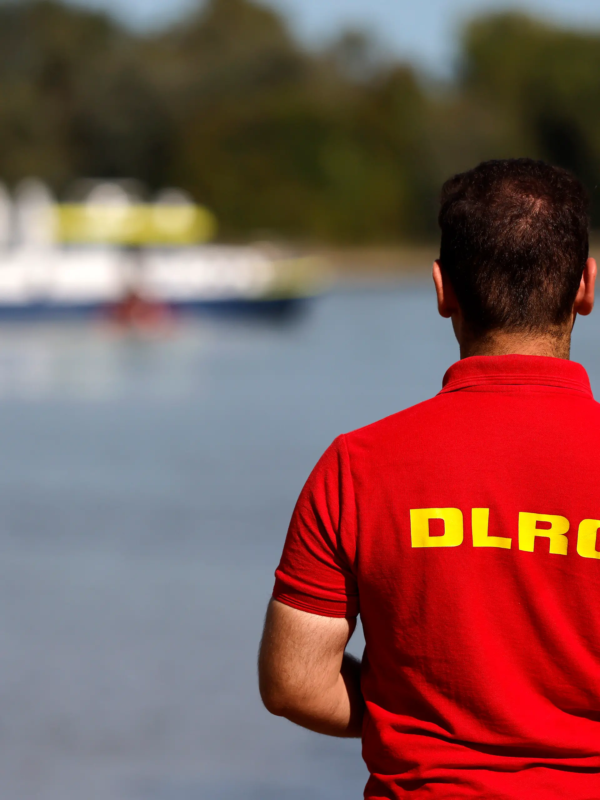 Ein Mitarbeiter der DLRG steht am Rheinufer, im Hintergrund ein Boot der Wasserschutzpolizei. Mitarbeiter des Ordnungsamts der Stadt Köln informieren derzeit am Rheinufer über die neuen Badeverbot-Regeln und sind an der Rodenkirchener Riviera präsent. Bei Verstößen sollen künftig bis zu 1000 Euro Bußgeld fällig sein. (Themenbild, Symbolbild) Köln, 19.09.2025