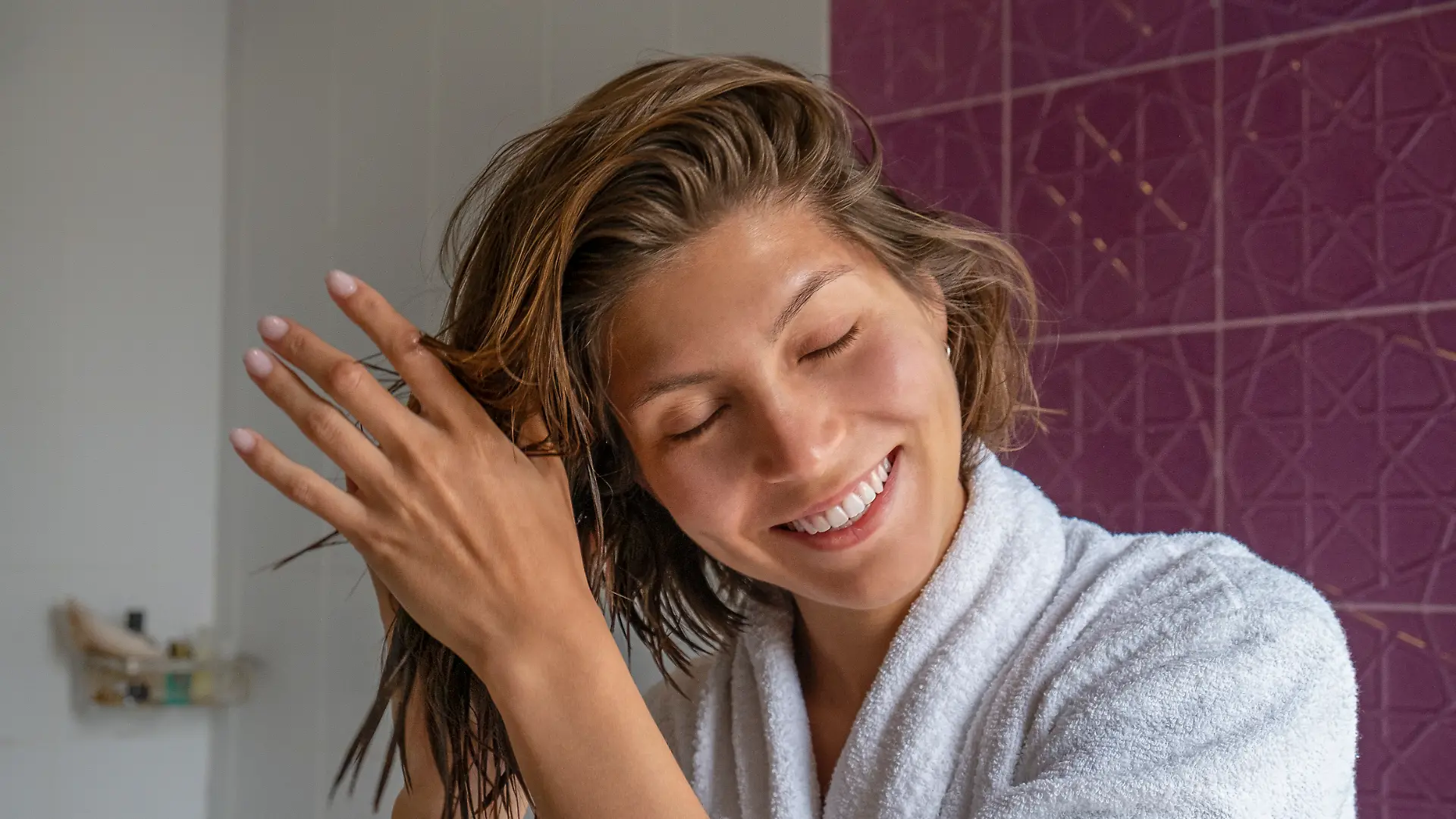 Frau stylt ihre Haare mit den Händen im Badezimmer.