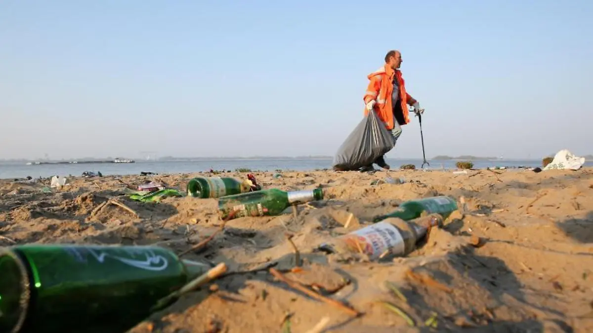 Mann sammelt Müll an einem Strand ein