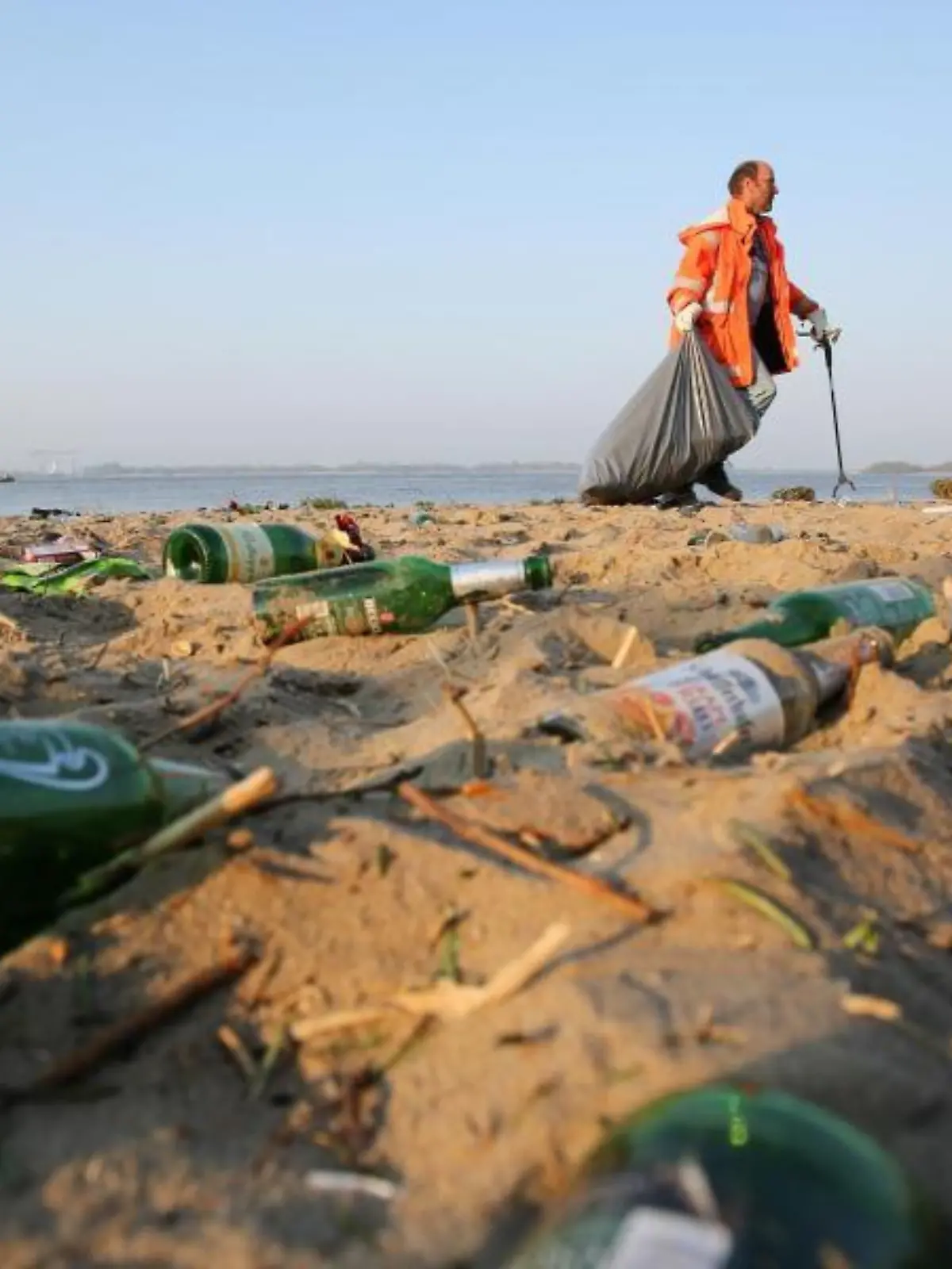 Mann sammelt Müll an einem Strand ein