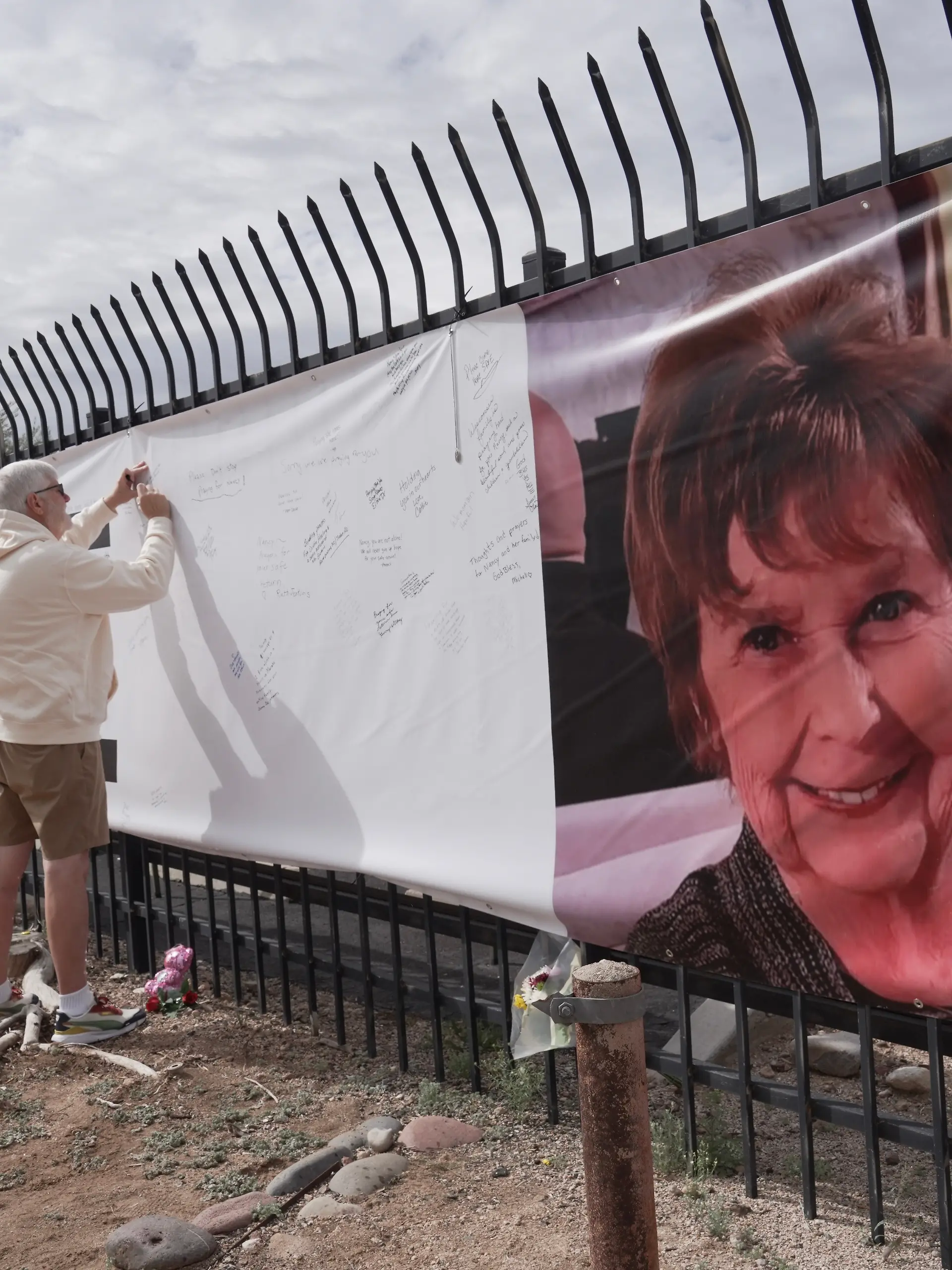 Jeff Robb, a Seattle resident wintering in Tucson, signs a banner supporting Nancy Guthrie in Tucson Ariz., on Friday, Feb. 13, 2026. (AP Photo/Ty ONeil)